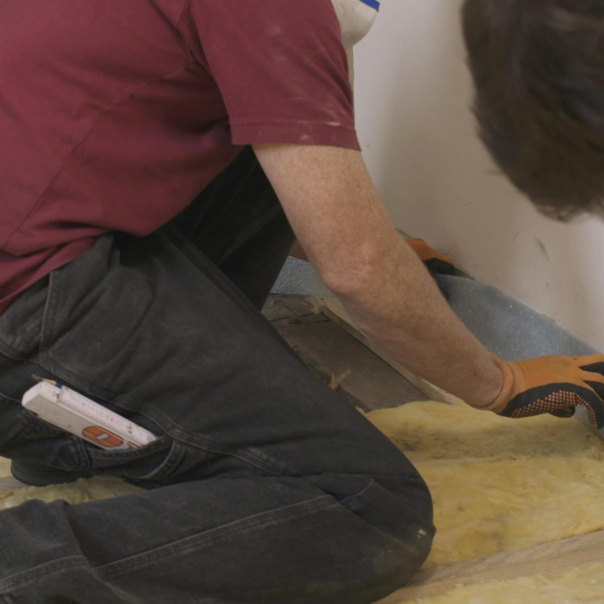 Randdämmstreifen wird von Handwerker an der Wand verklebt.