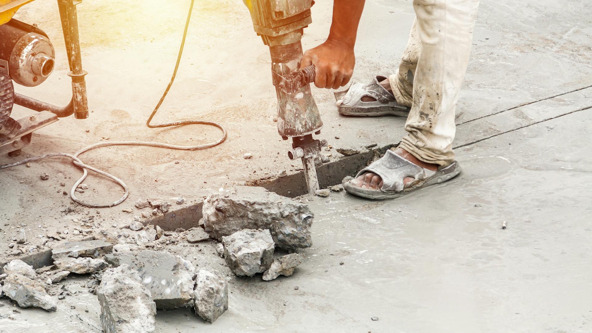 Osoba frézuje drážku do betónu