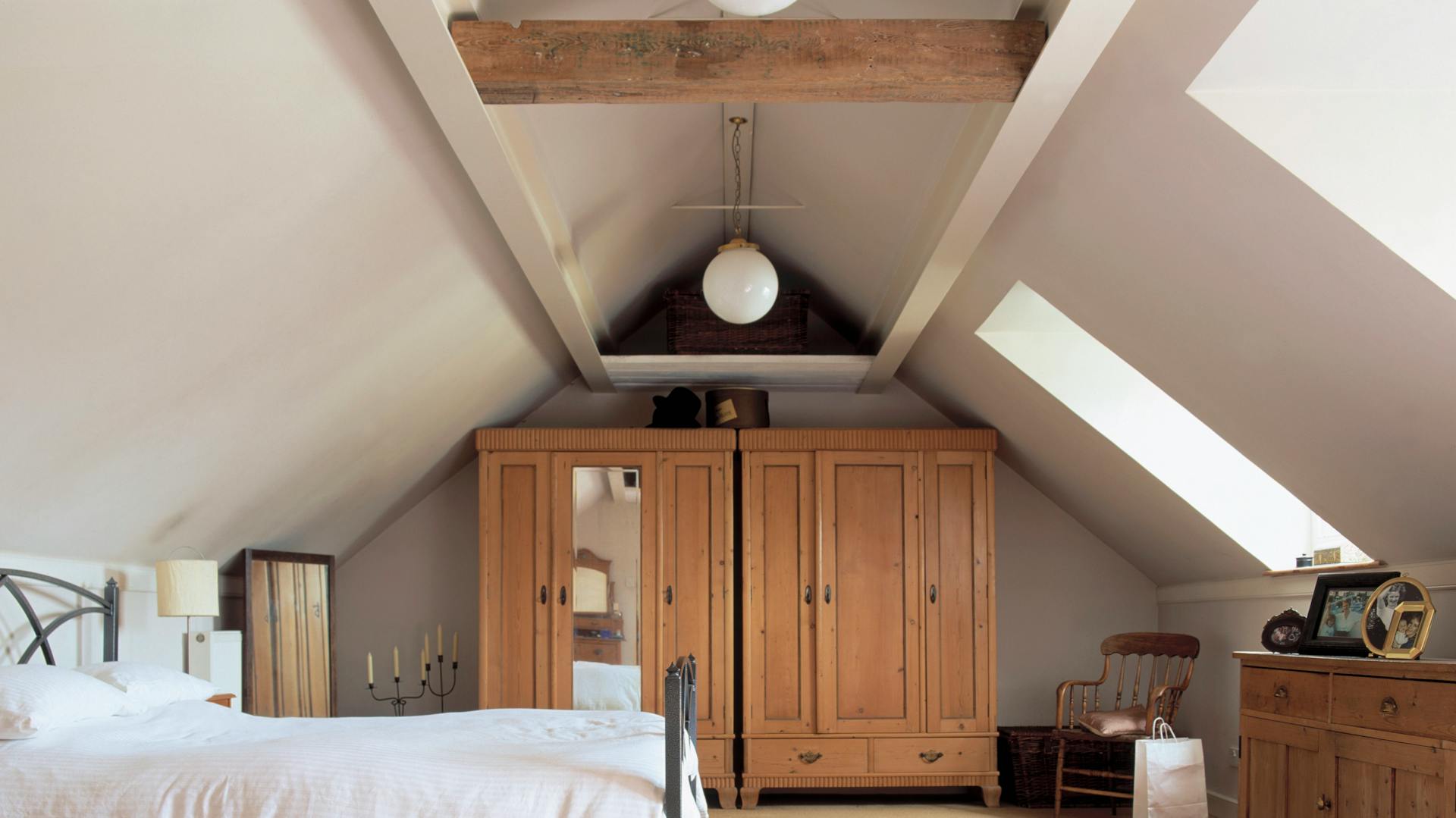 Hálószoba ággyal, szekrényekkel és komóddal a padlástérben.