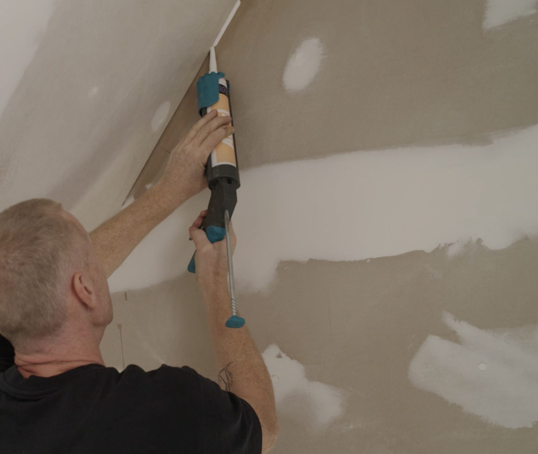 Ein Handwerker füllt Fugenübergänge auf. 