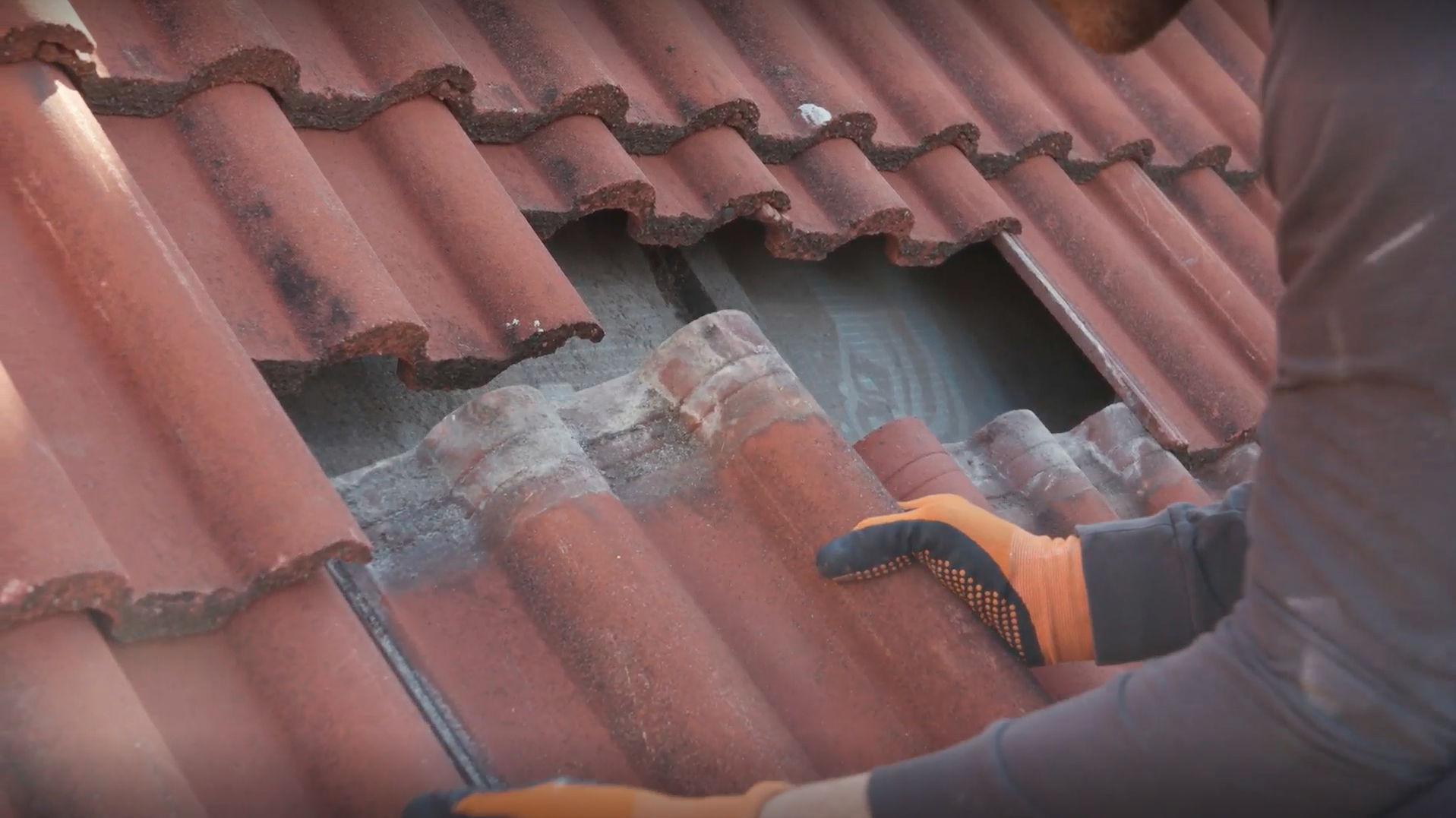 Pracovník ukladá nové strešné škridly.