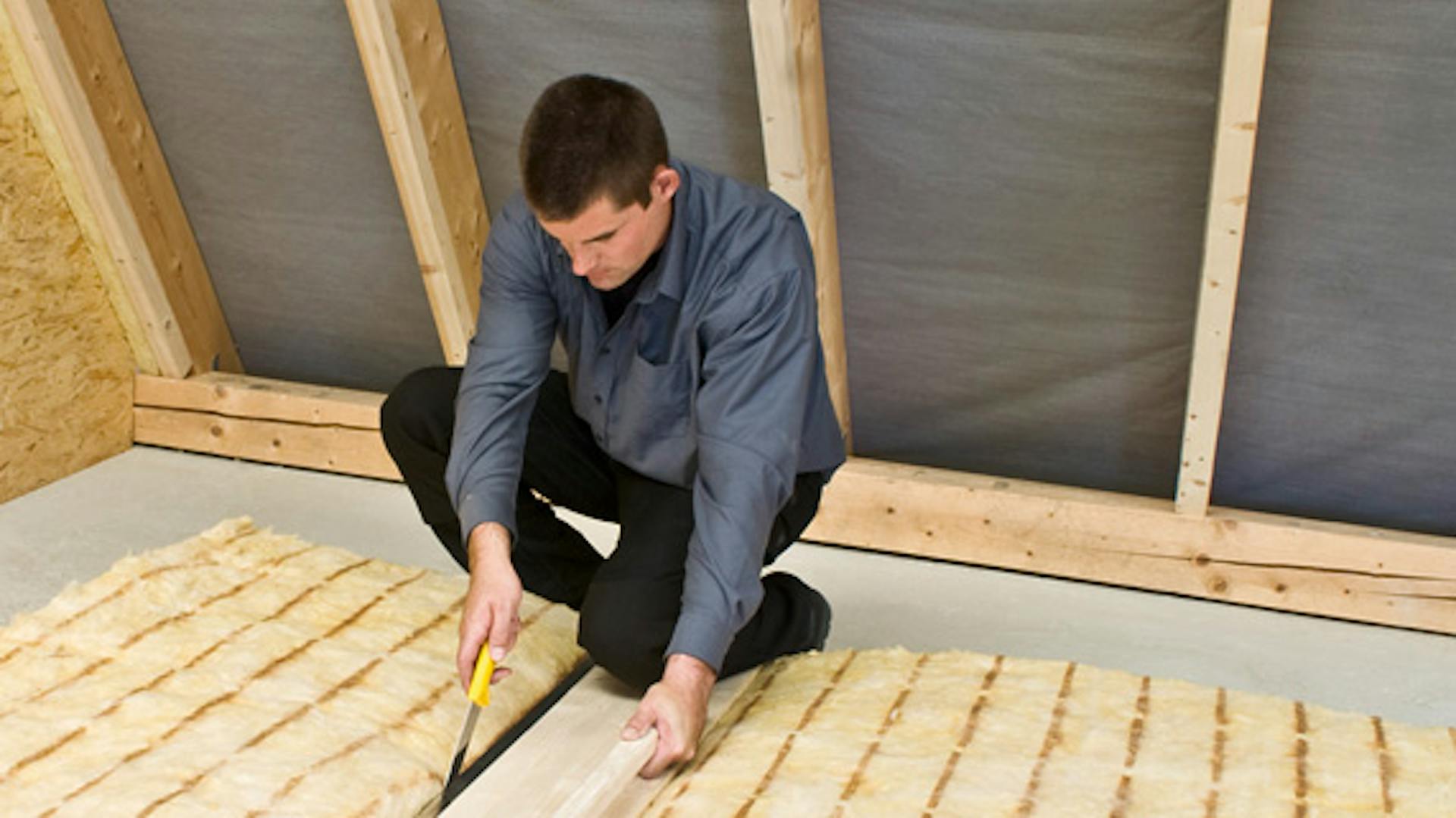 Un appassionato del fai da te installa l’isolamento delle travi per isolare l’interno del tetto.