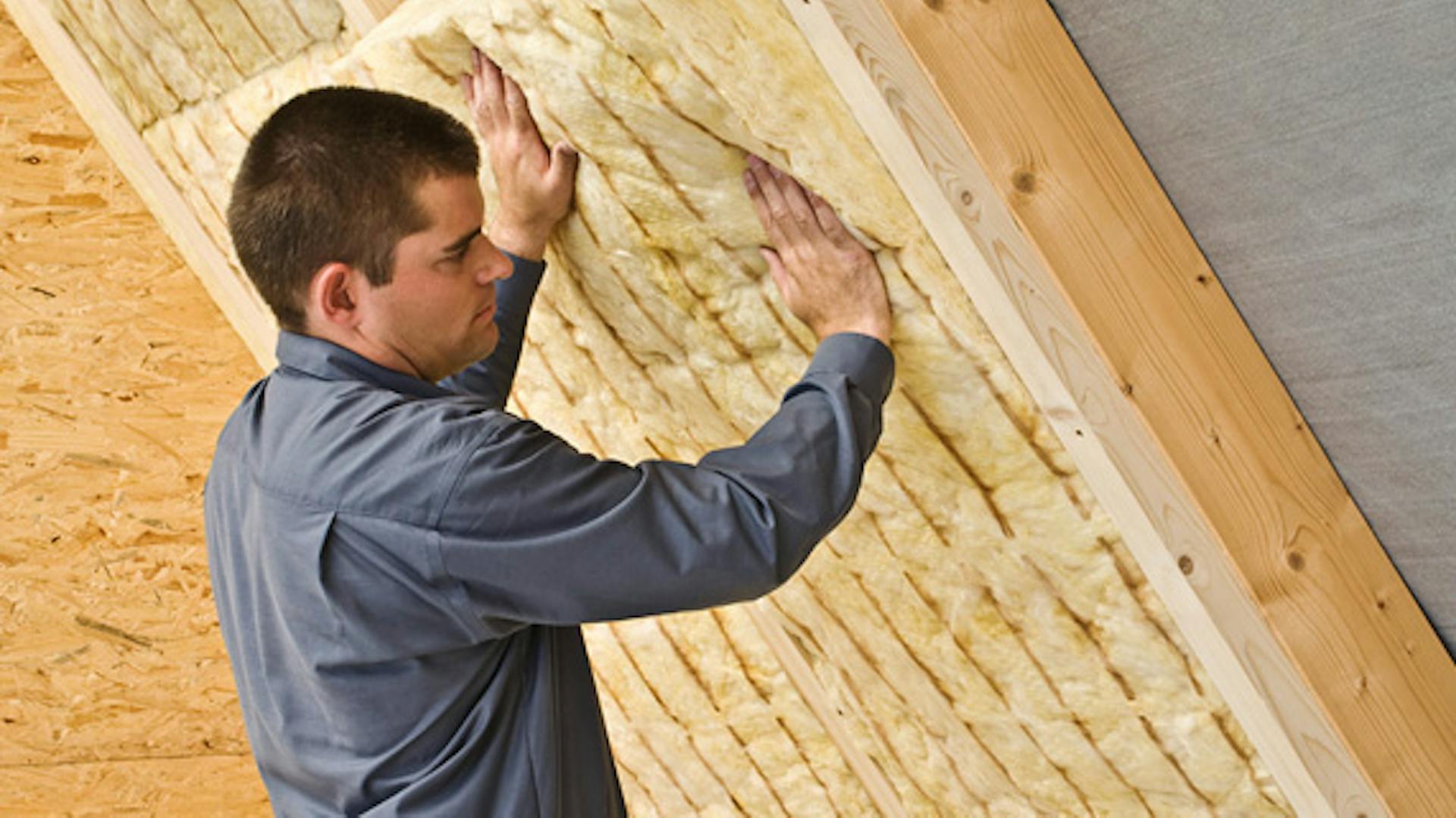 Heimwerker dämmt Dach mit Klemmfilzmatte.