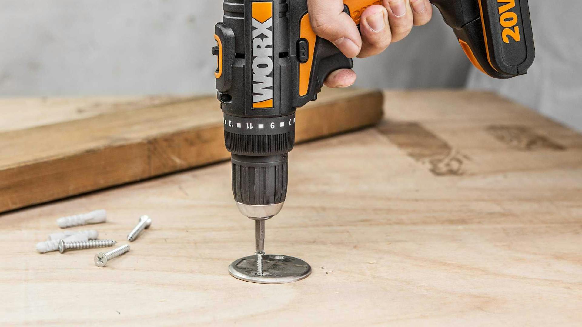 Hand schraubt mit Akkuschrauber Schraube in Holz