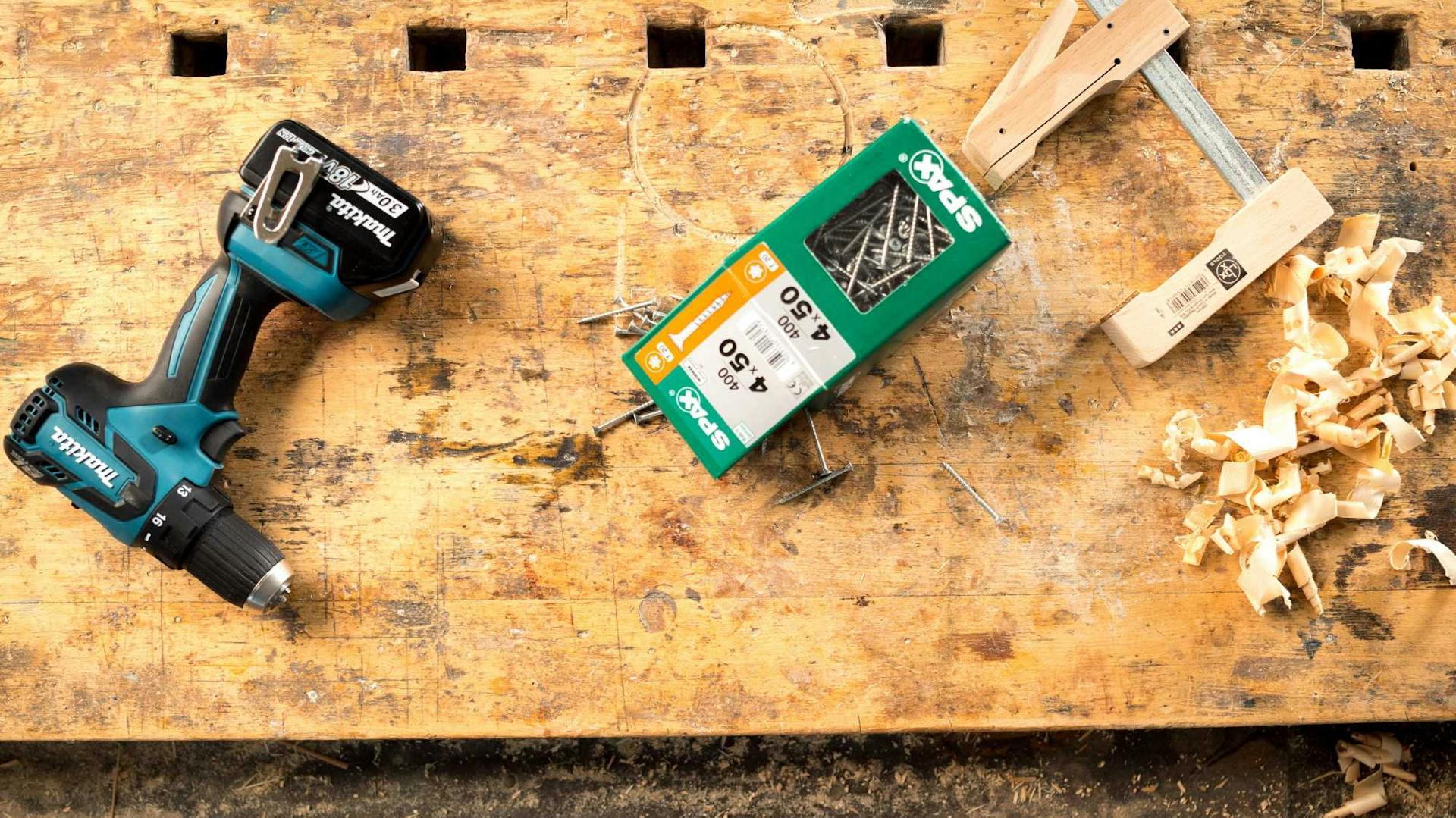 Akkuschrauber, Schrauben und Zwinge auf Werkbank