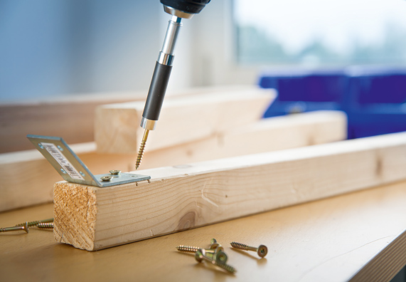 Akumulátorový šroubovák s vrutem na dřevěném nosníku