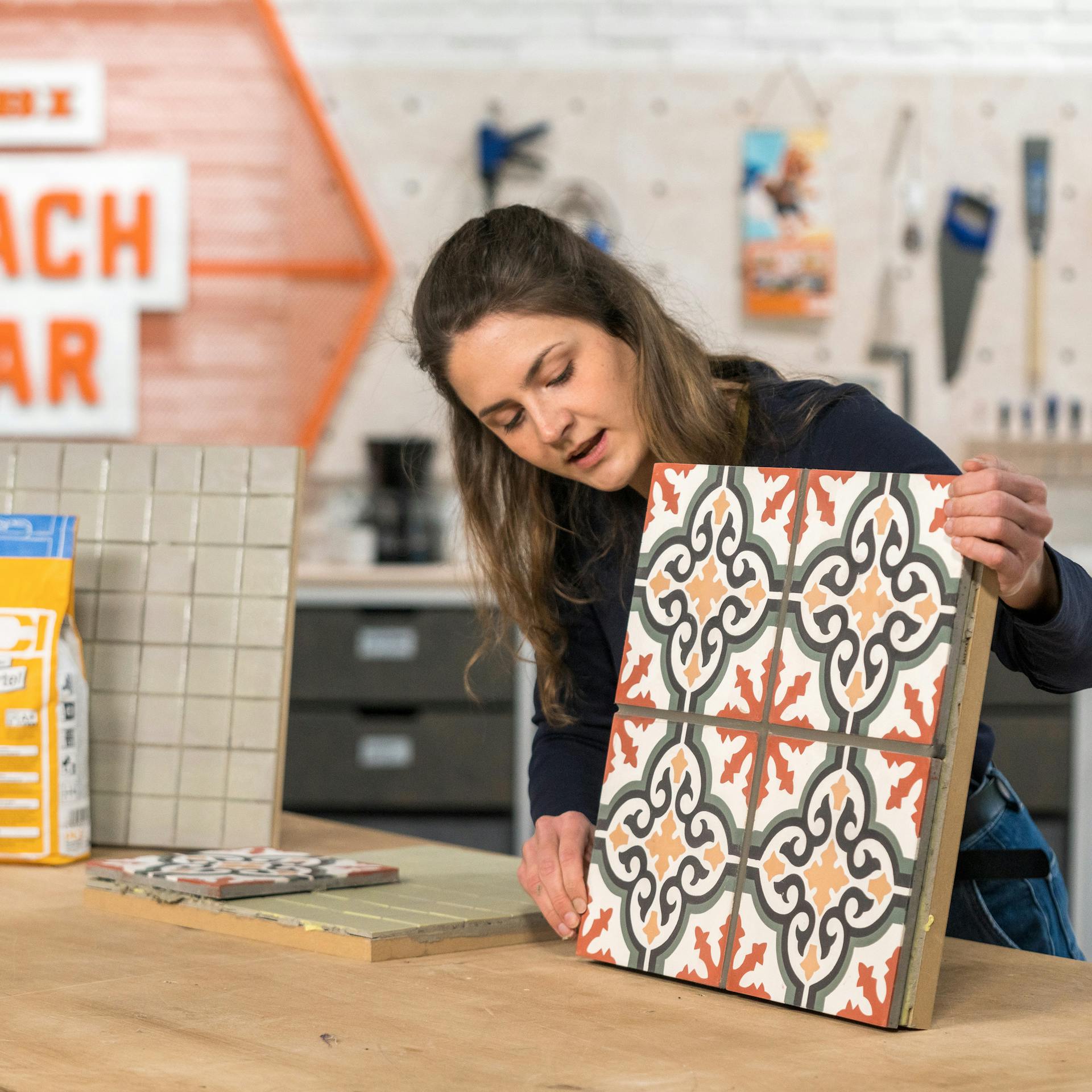 Handwerker hält verklebte Fliesen in der Hand.