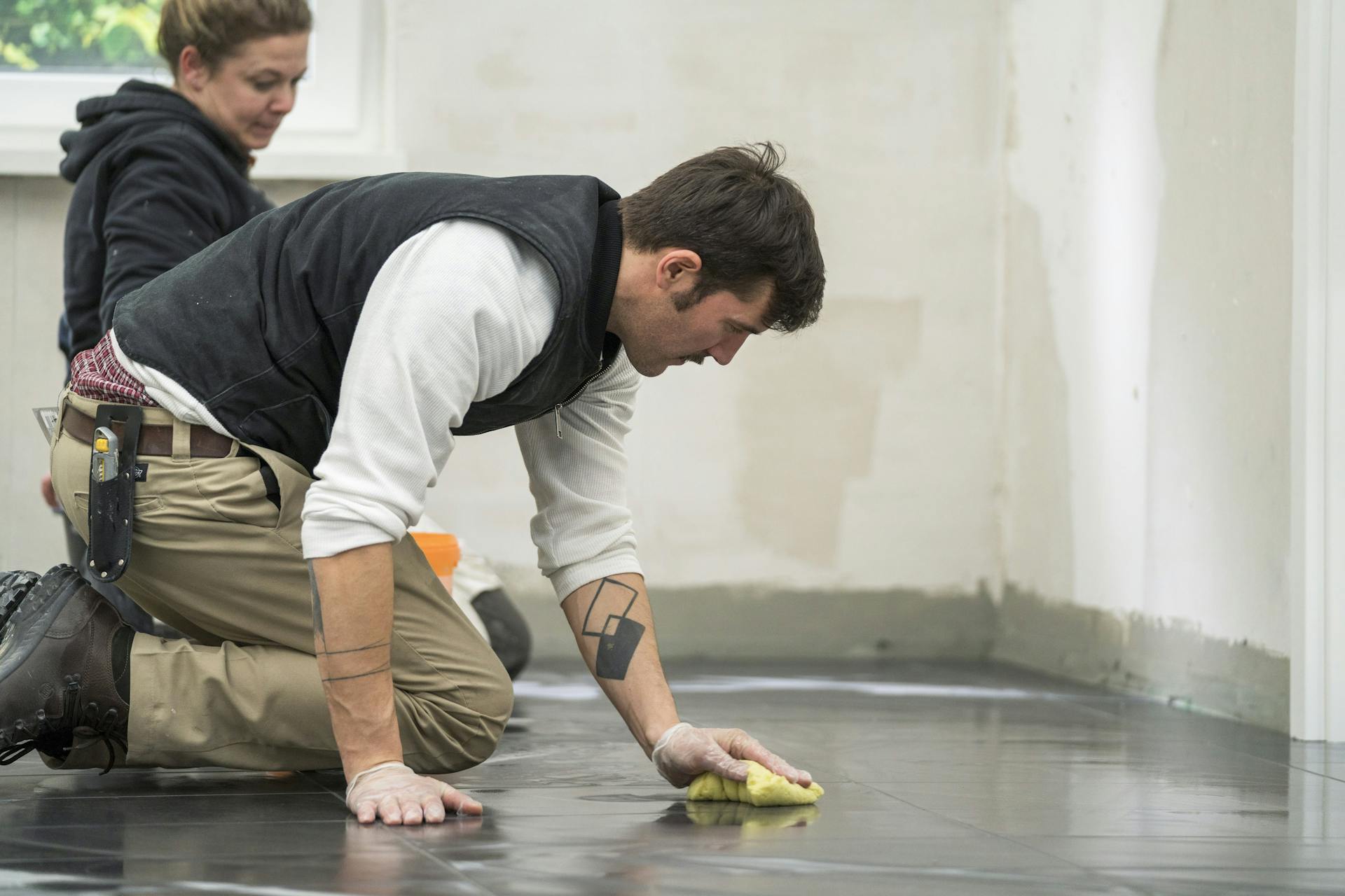 L’appassionato del fai-da-te pulisce le piastrelle con una spugna.