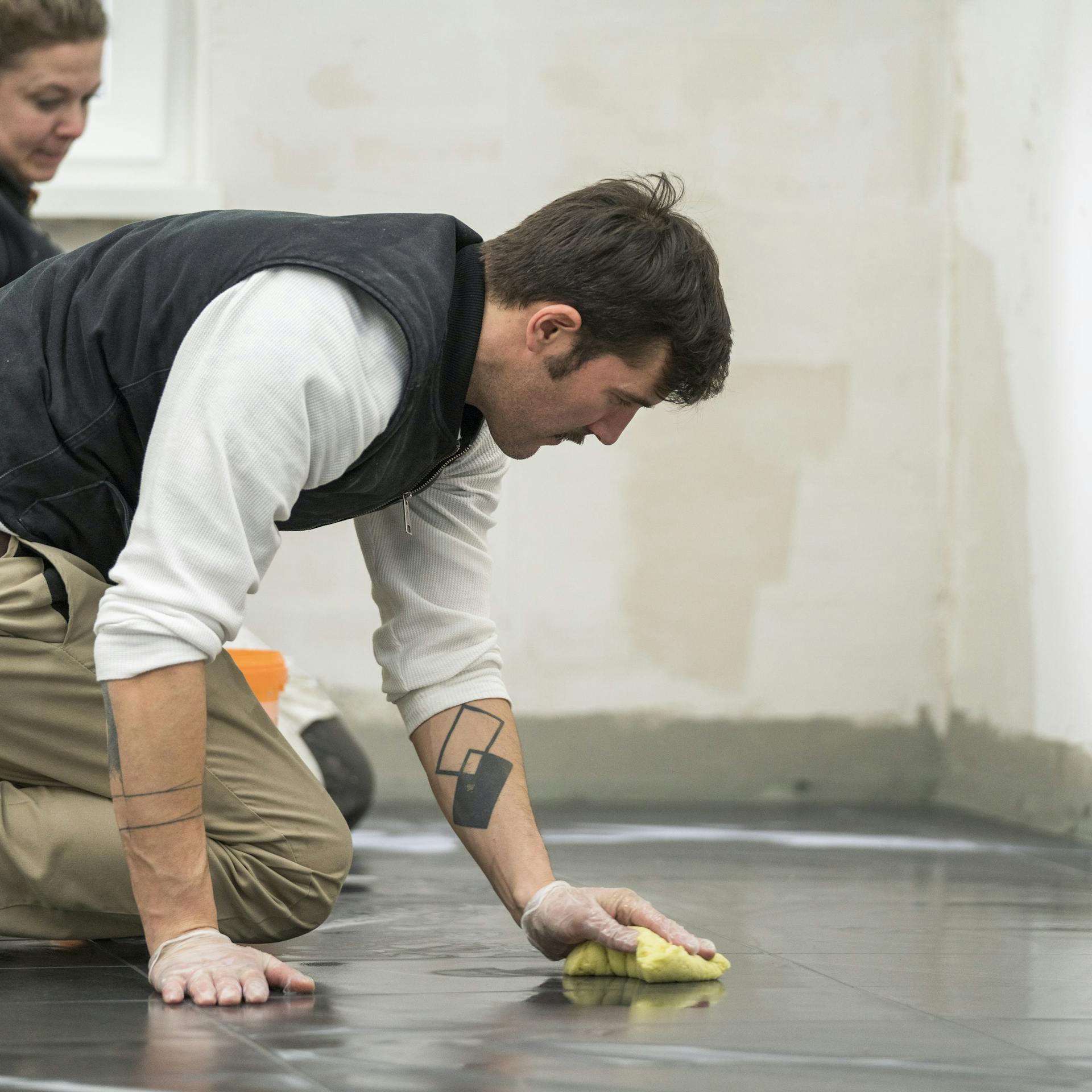 Heimwerker reinigst die Fliesen mit einem Schwamm.