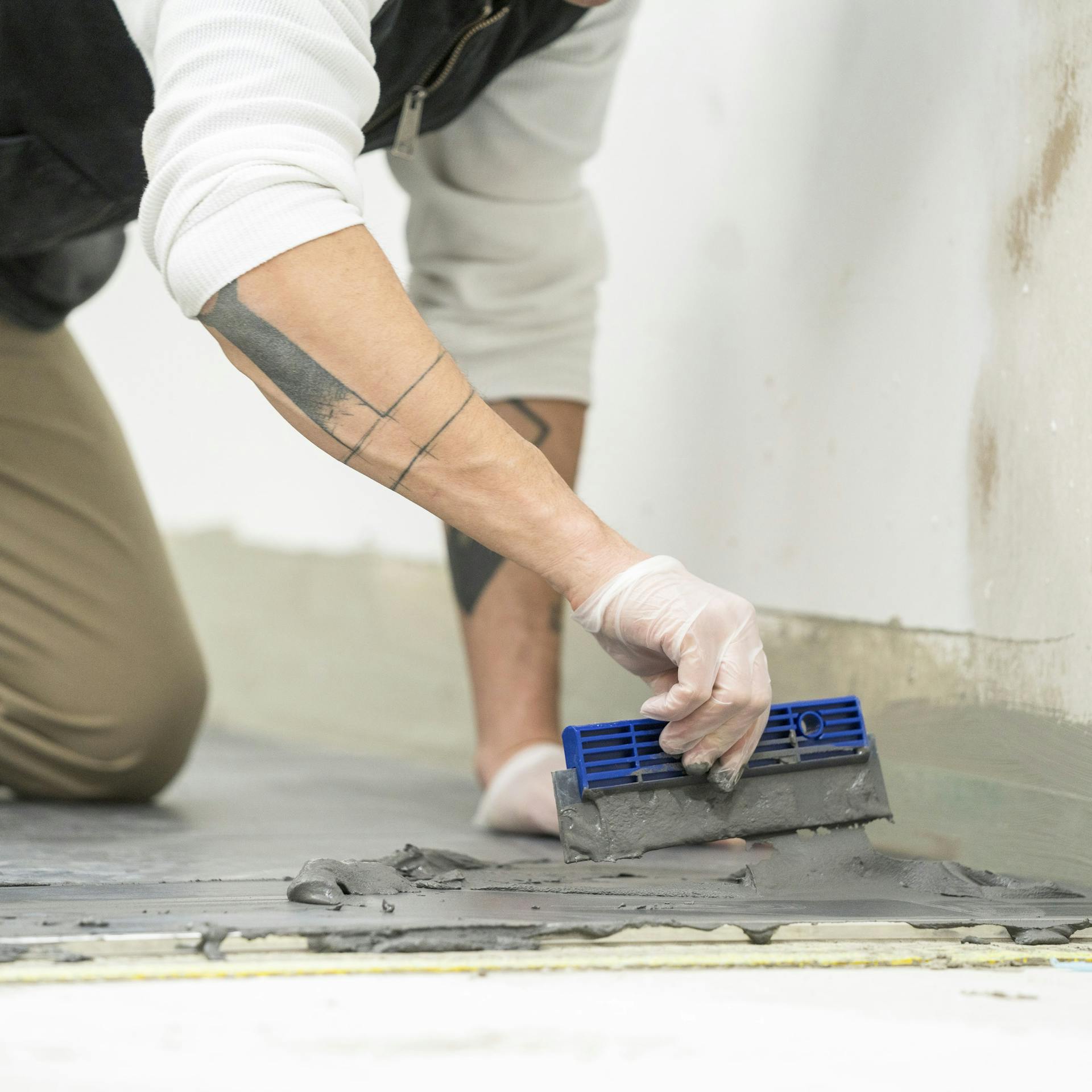 Heimwerker trägt Mörtel auf die Fliesen auf.