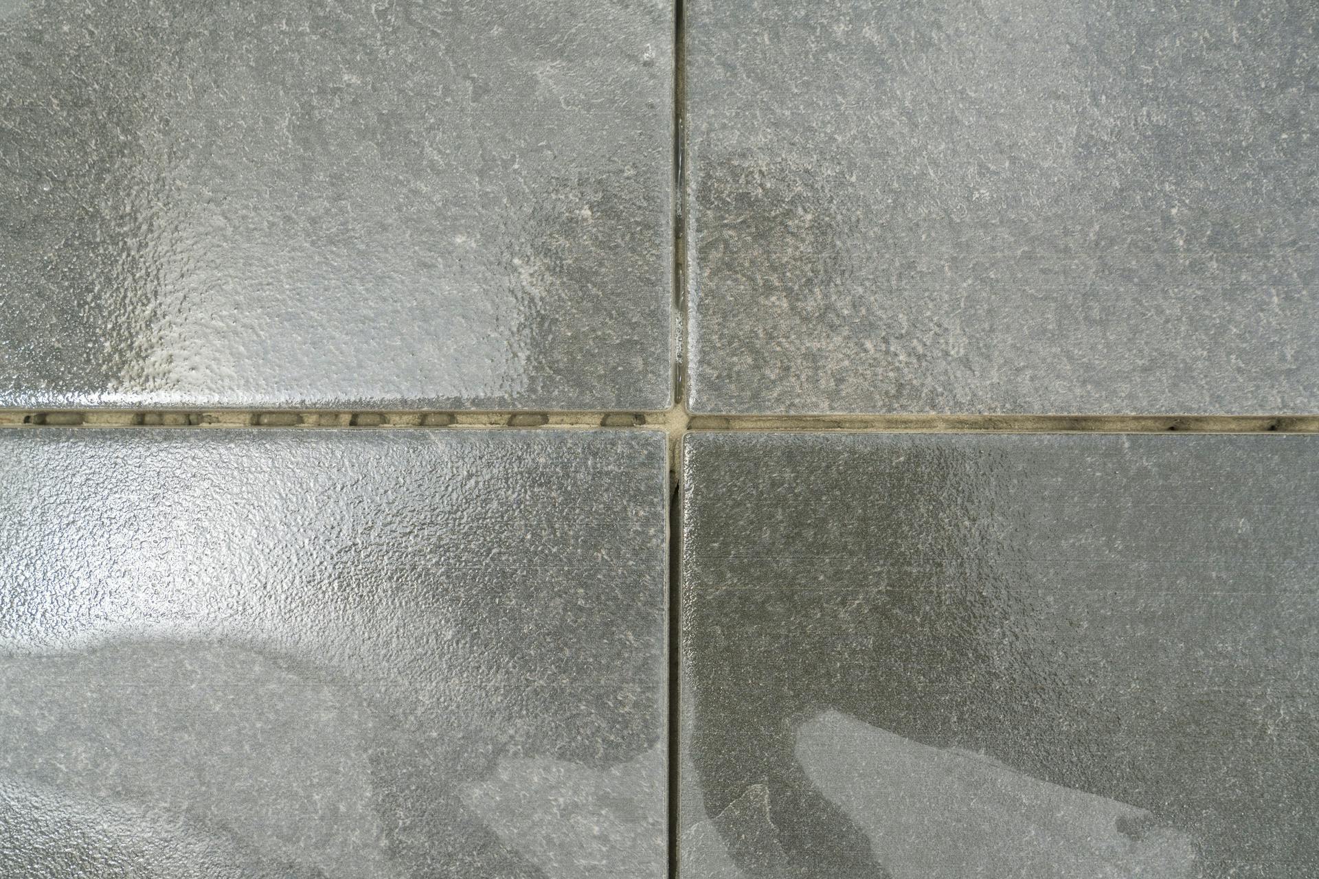 Piastrelle grigie con residui di malta.