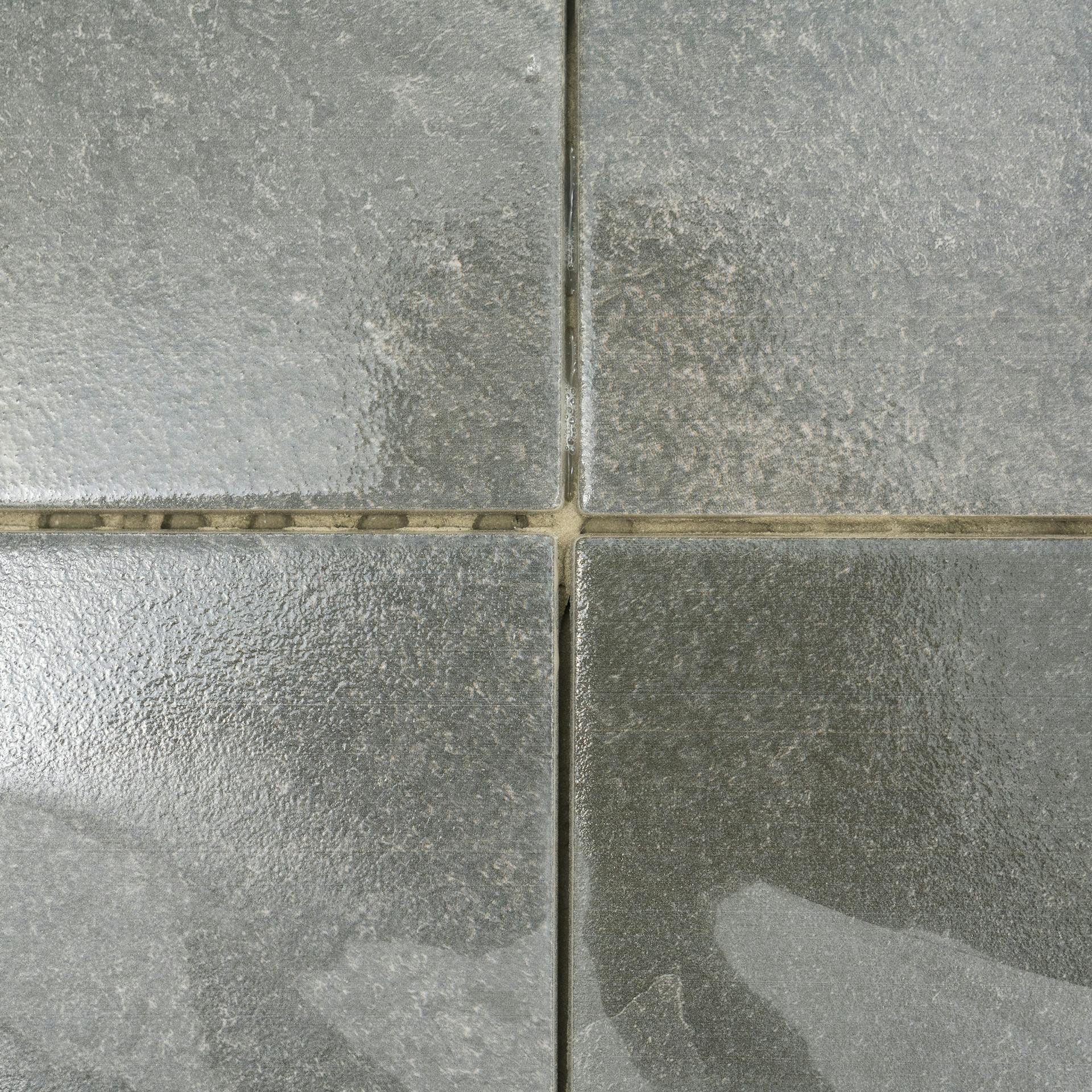 Graue Fliesen mit Mörtelresten.