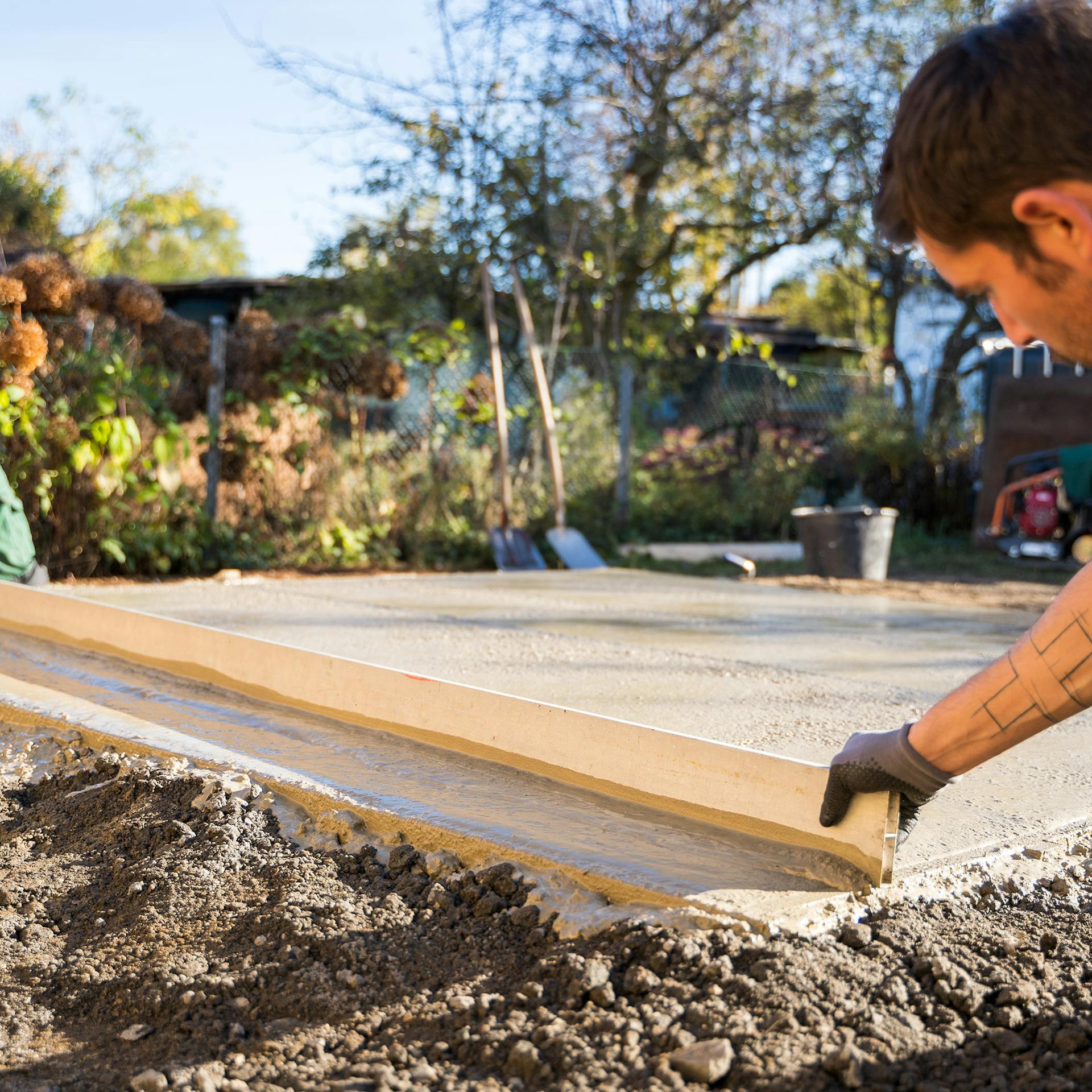 Zwei Männer ziehen die Betonfläche ab.