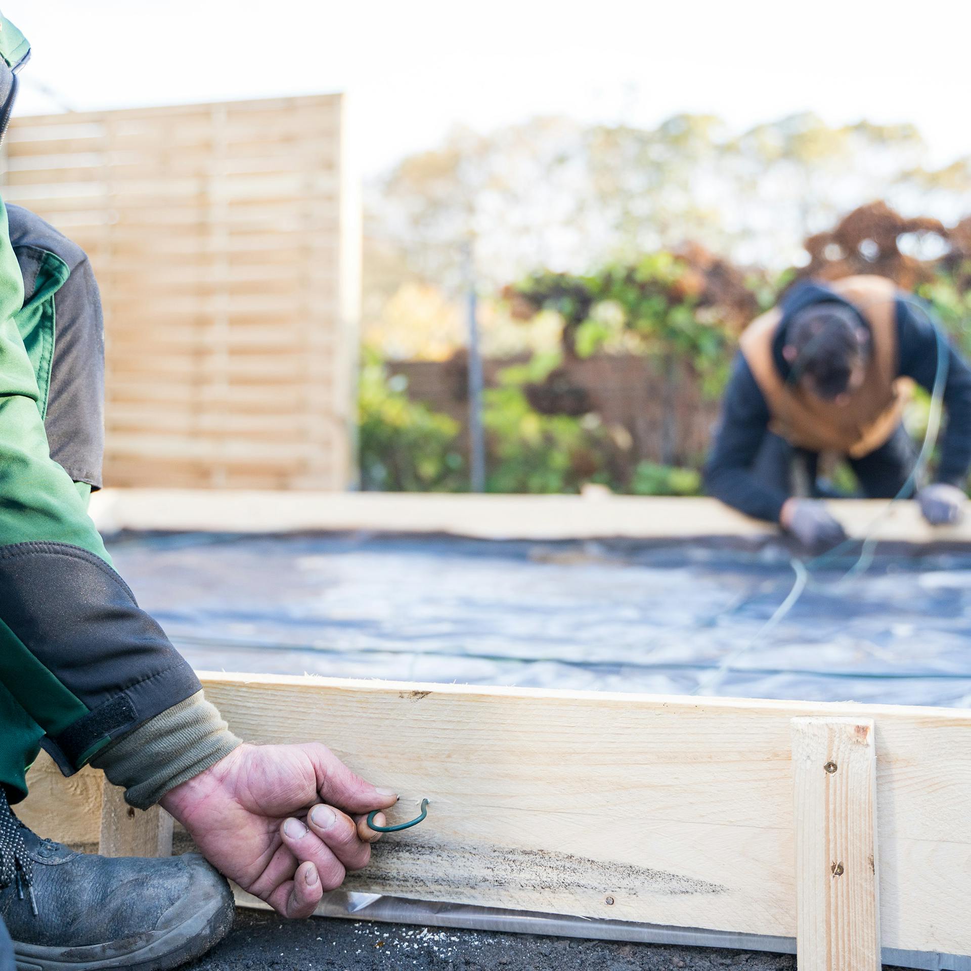 Zwei Personen ziehen Draht durch die Verschalung.
