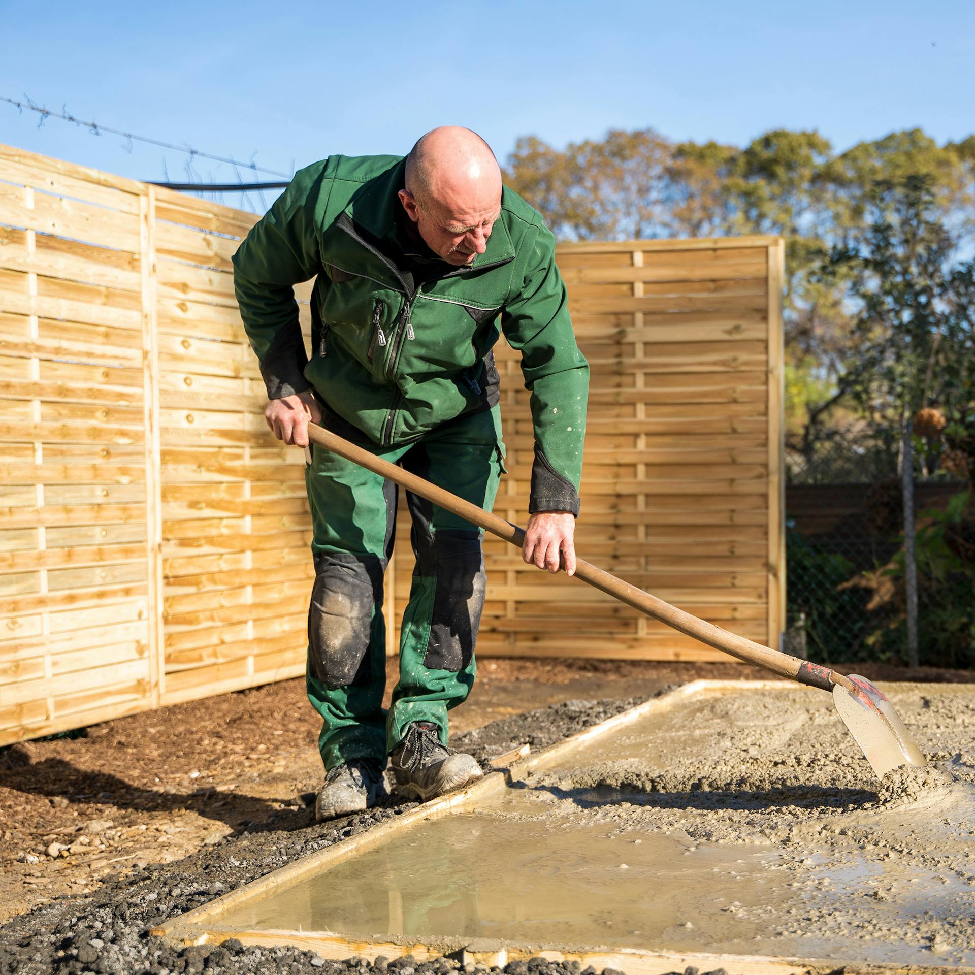 Heimwerker verdichtet in Schalung eingefüllten Beton mit der Schaufel.