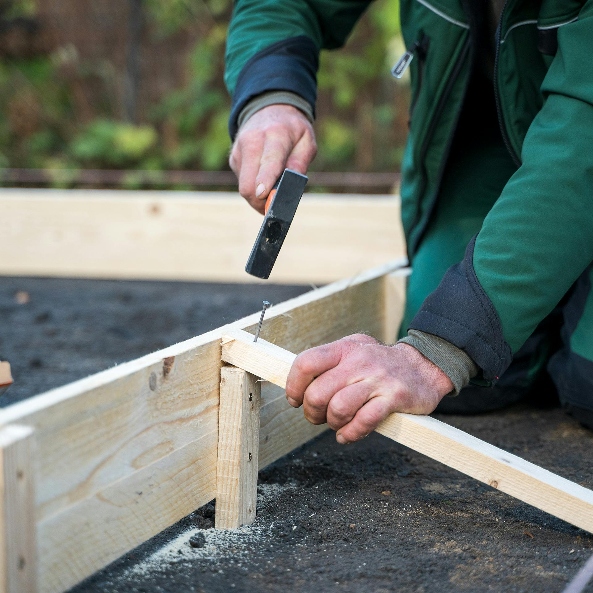 Jemand nagelt Stützlatten an eine Verschalung.