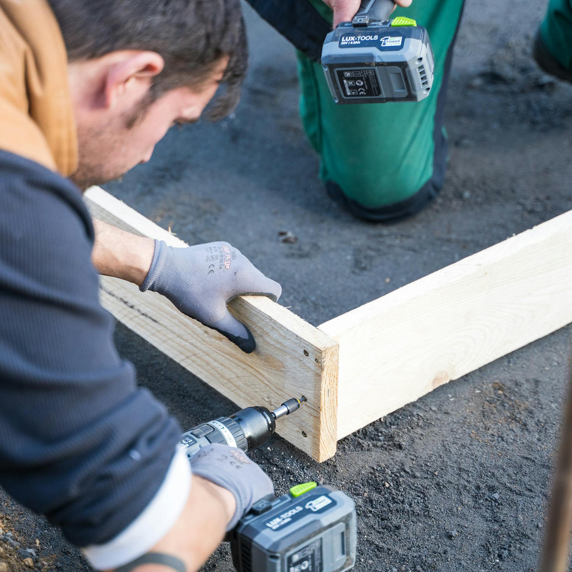 Ein Mann verschraubt Schalbretter.