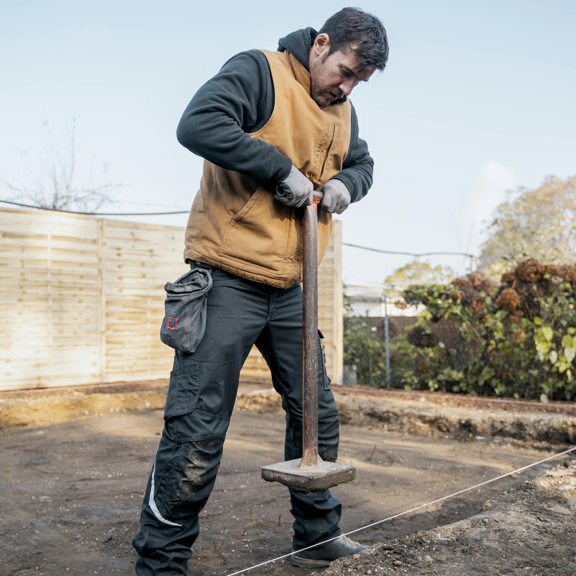 Jemand verdichtet den Boden mit einem Handstampfer