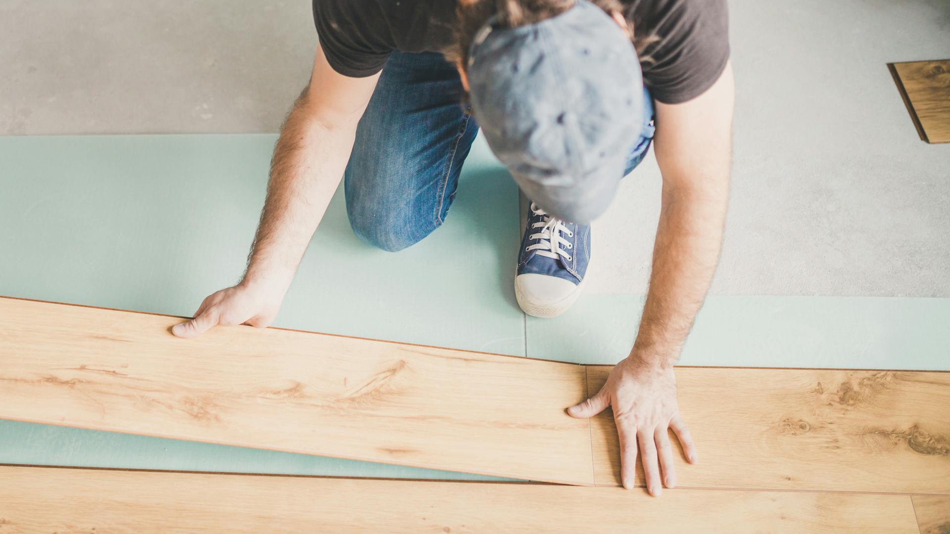 Ein Mann verlegt Klicklaminat auf einem gedämmten Boden