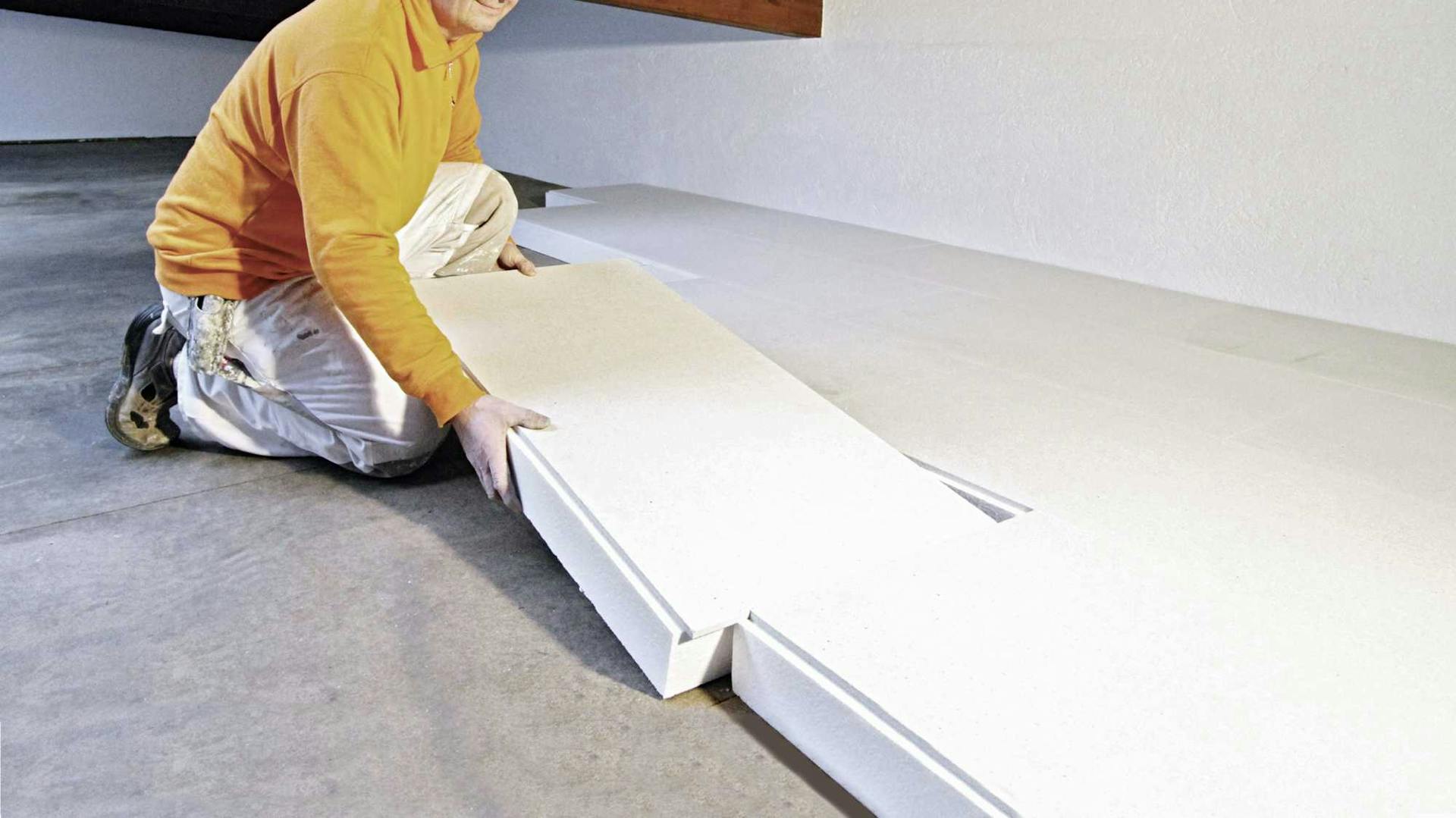 Mann verlegt Dämmplatten auf Boden