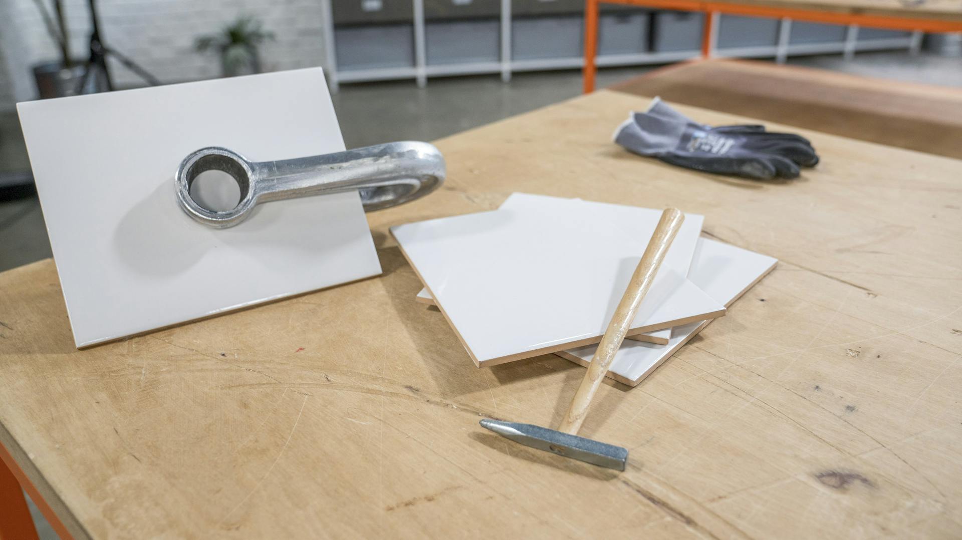 Fliesenhammer liegt mit weißen Fliesen auf dem Tisch.