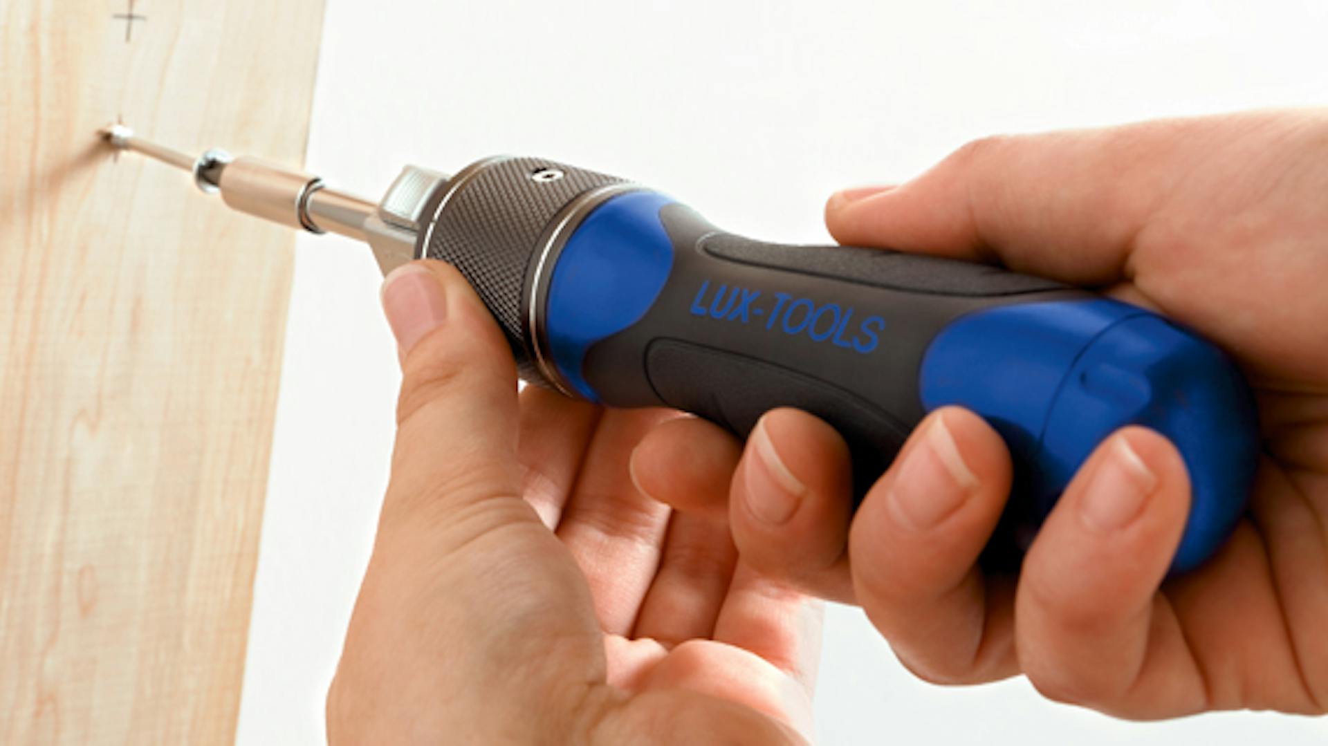 Hände, die mit einem Schraubendreher Schraube in Holz bohren