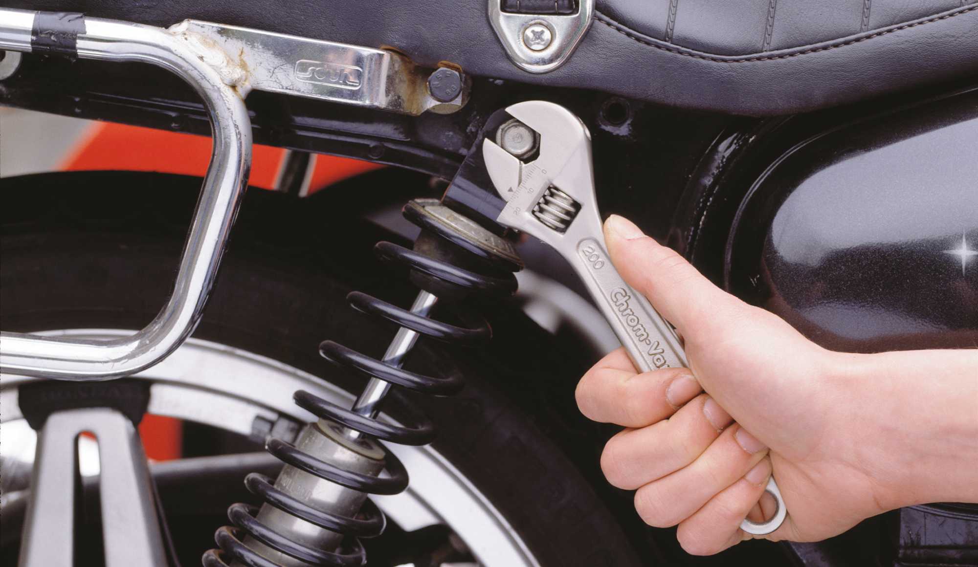 Hand mit Schraubenschlüssel an Motorrad