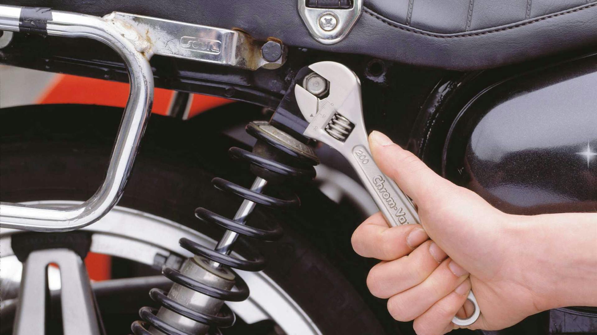 Hand mit Schraubenschlüssel an Motorrad