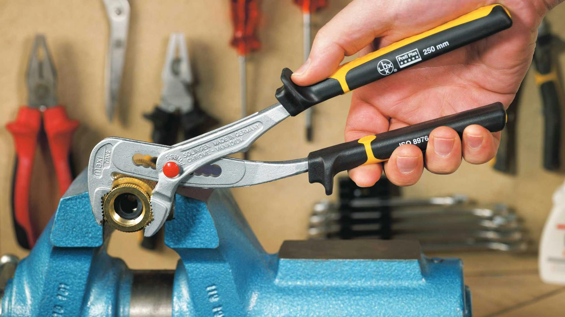 Hand kneift Rohr mit Zange