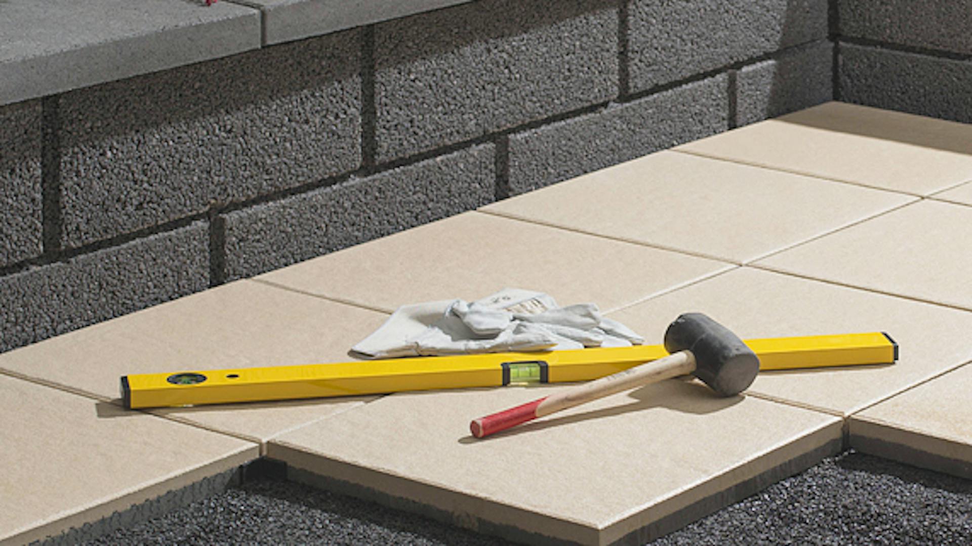 Wasserwaage und Hammer auf Fliesen