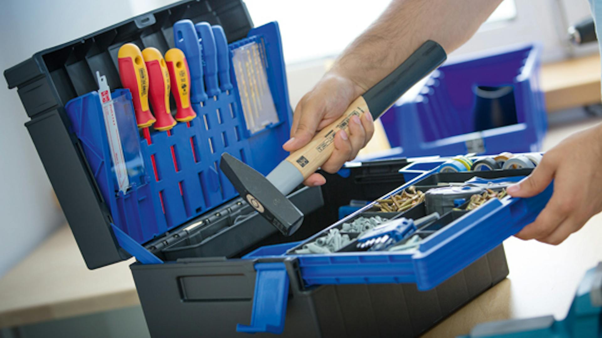 Werkzeugkoffer und eine Hand, die einen Hammer hält