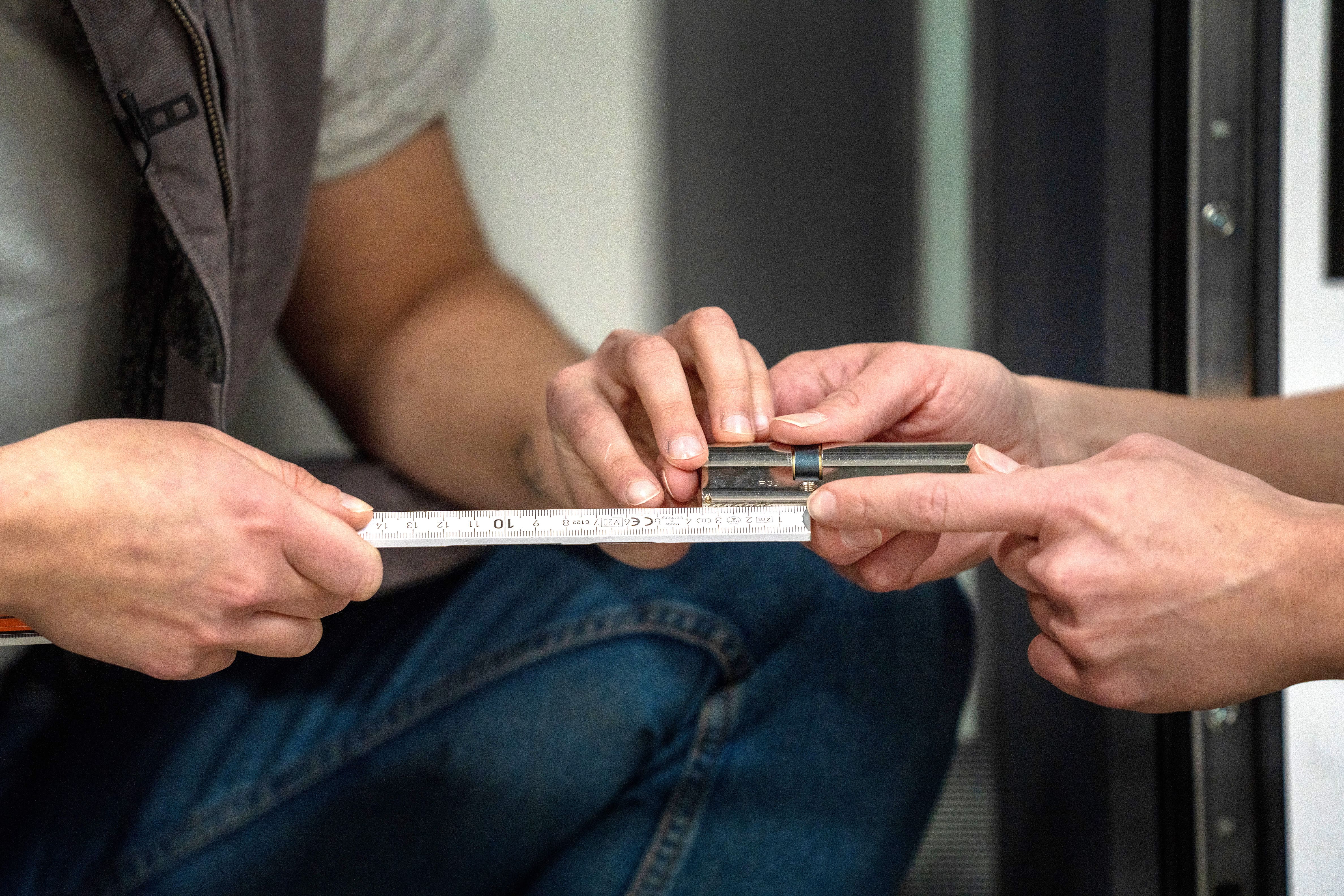 Heimwerker messen die Abstände von der Stellschraube des Zylinders zu beiden Außenseiten. 