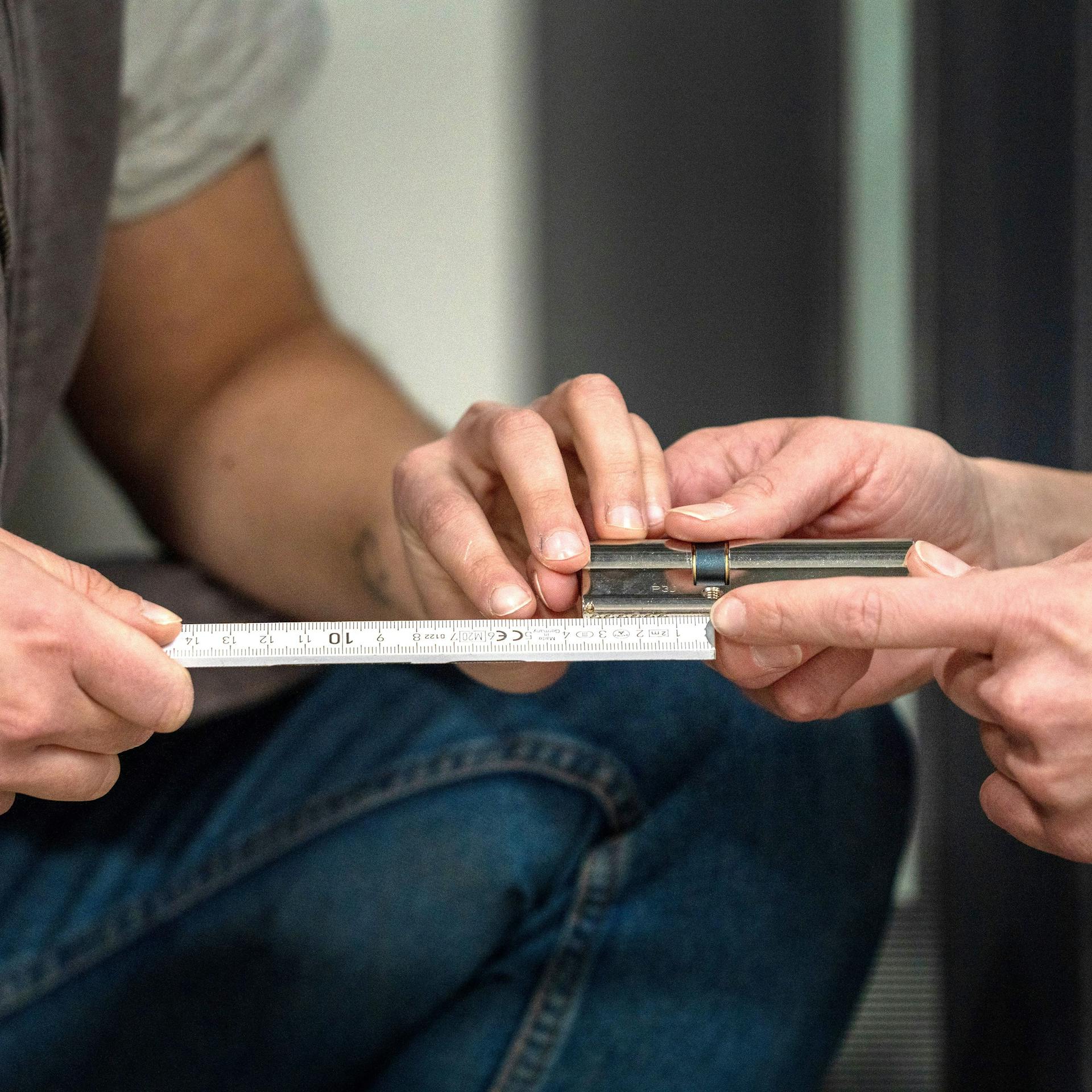 Heimwerker messen die Abstände von der Stellschraube des Zylinders zu beiden Außenseiten.