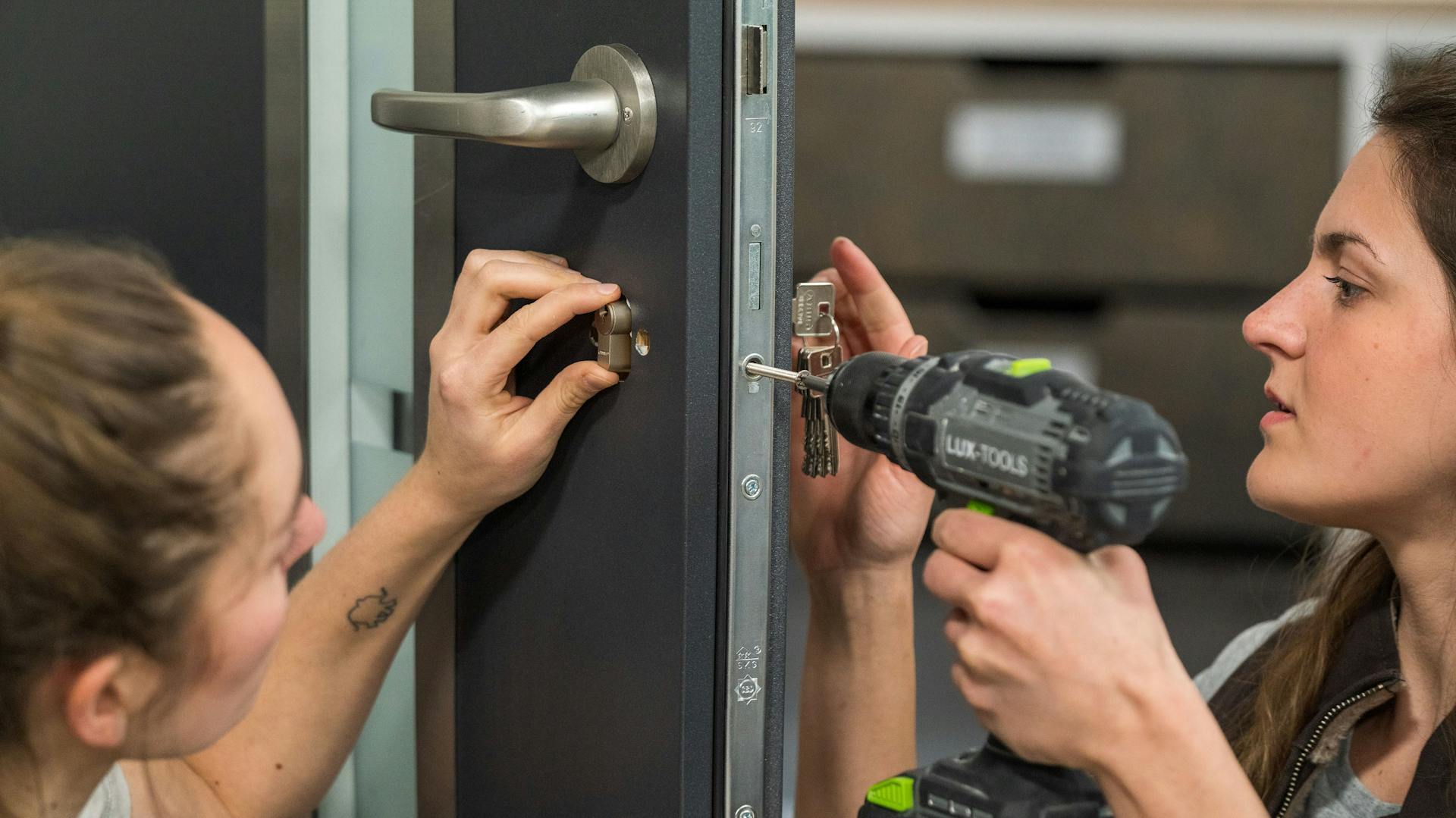 Zwei Frauen wechseln das Profilzylinderschloss in einer Haustür.