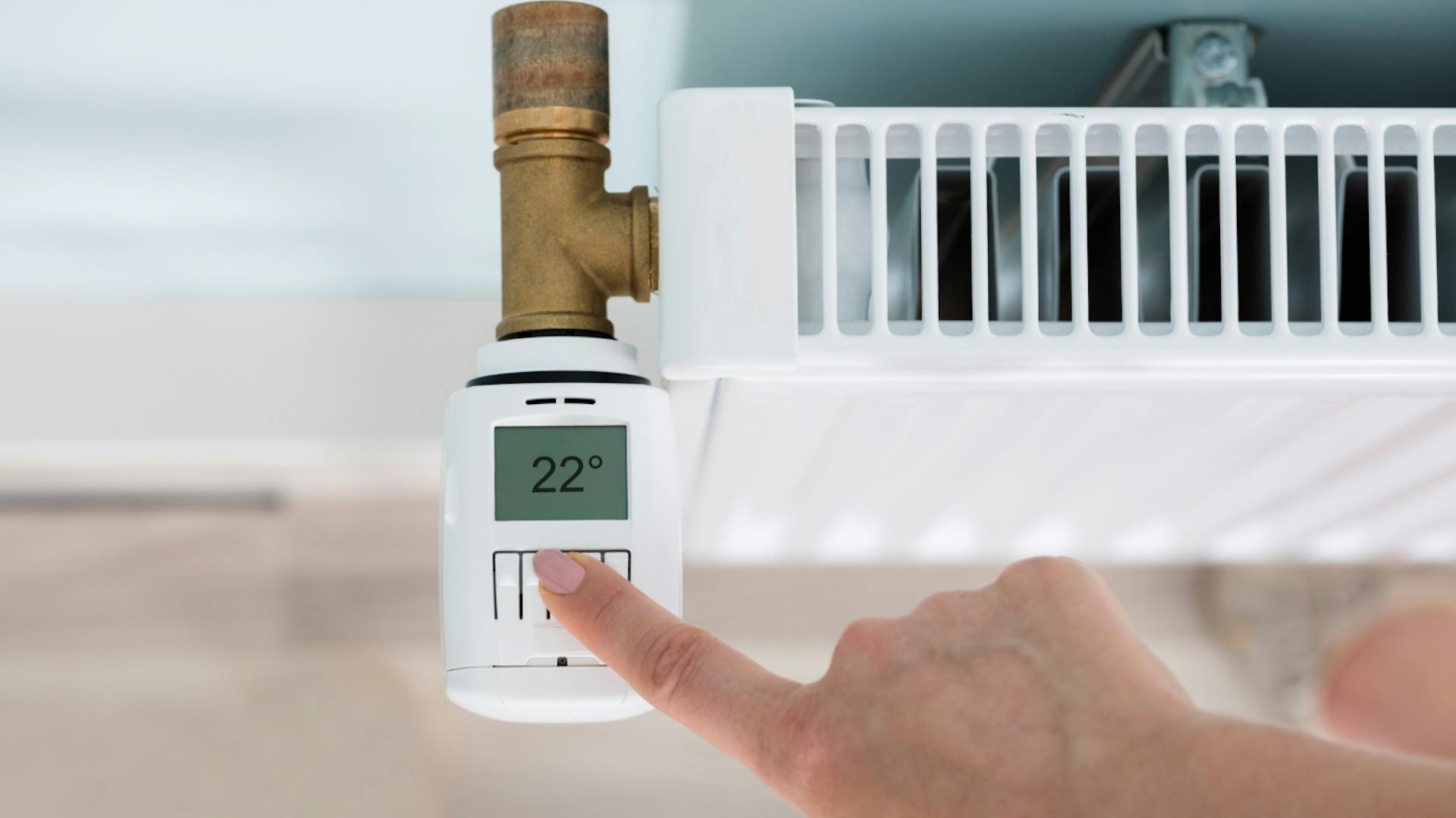 Una persona aziona il termostato elettrico sui radiatori