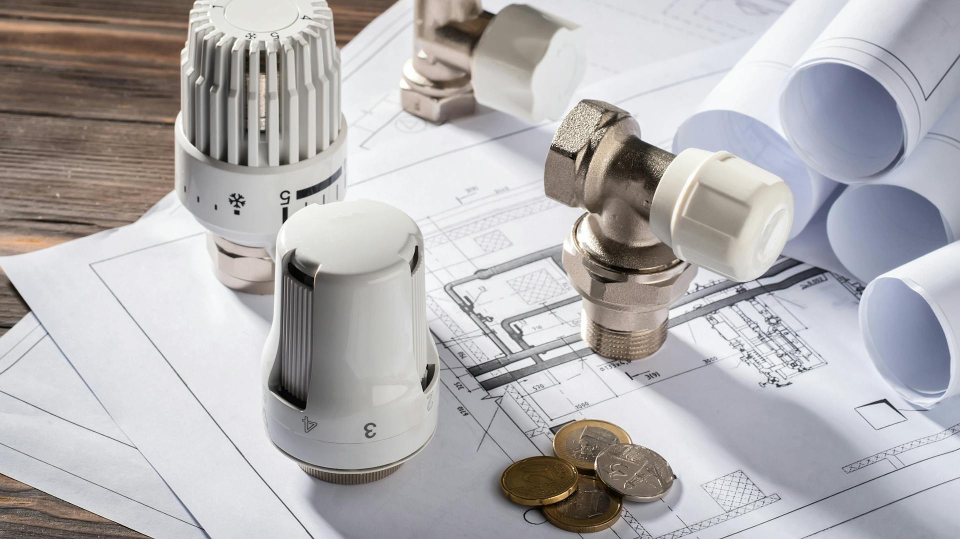 Valvole per radiatori, raccordi e monete su un progetto di costruzione.