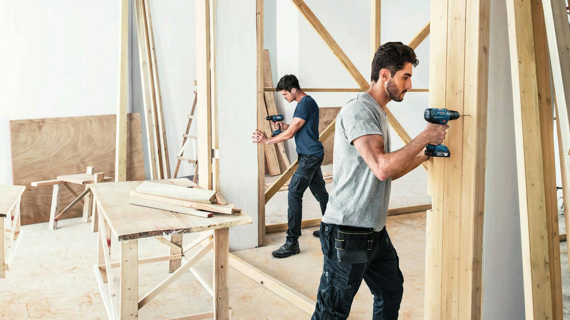 Pracovníci s náradím a drevenými doskami pri stavbe v interiéri