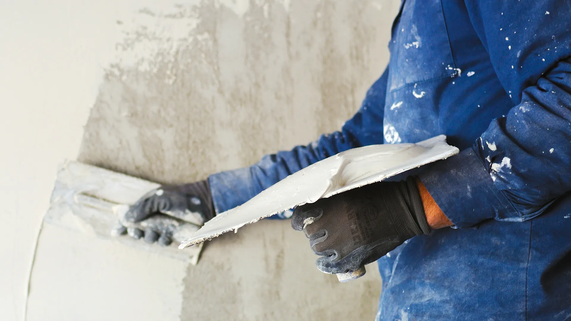 Muž nanáší hladítkem omítku.