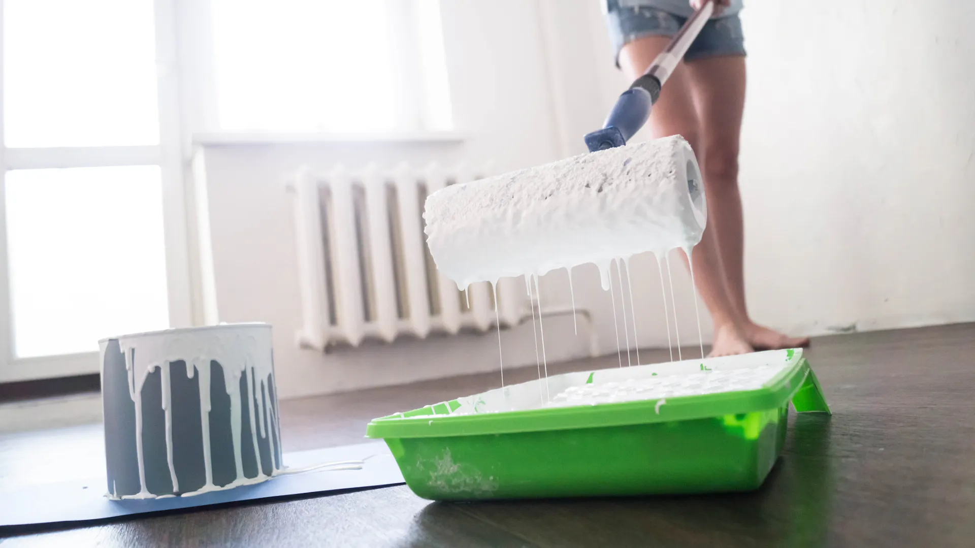 Žena namáčí váleček v interiérové barvě.