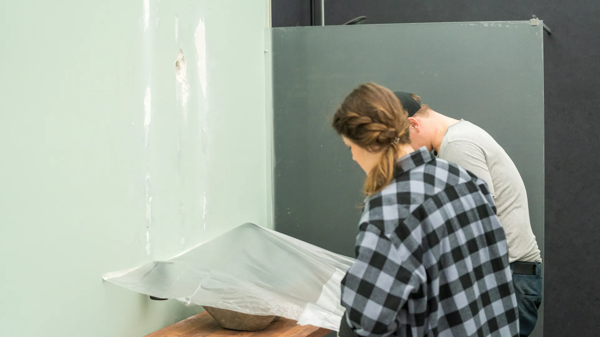 Dvě osoby zakrývají vše krycí netkanou textilií.