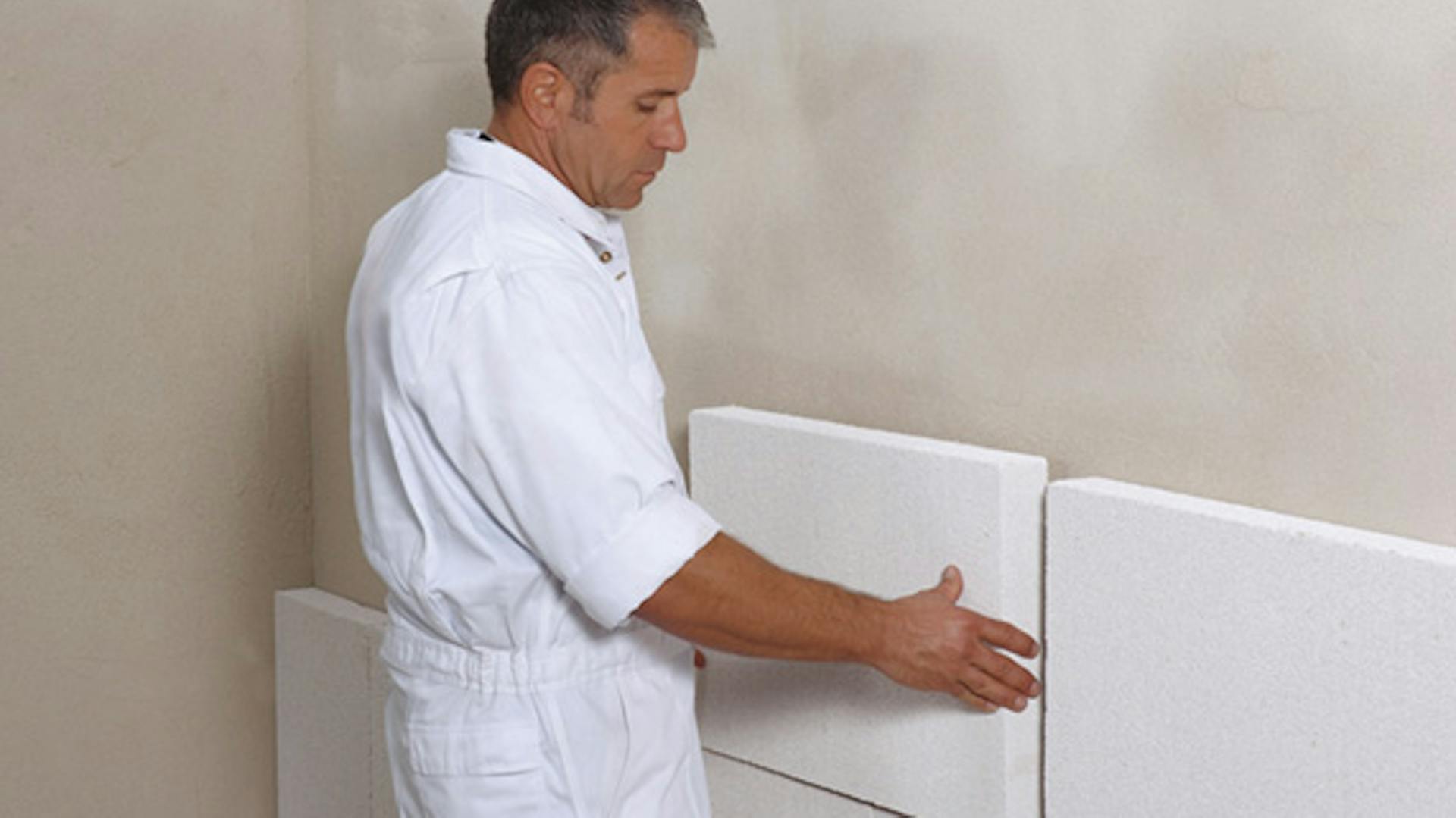 Ein Mann dämmt eine Innenwand.