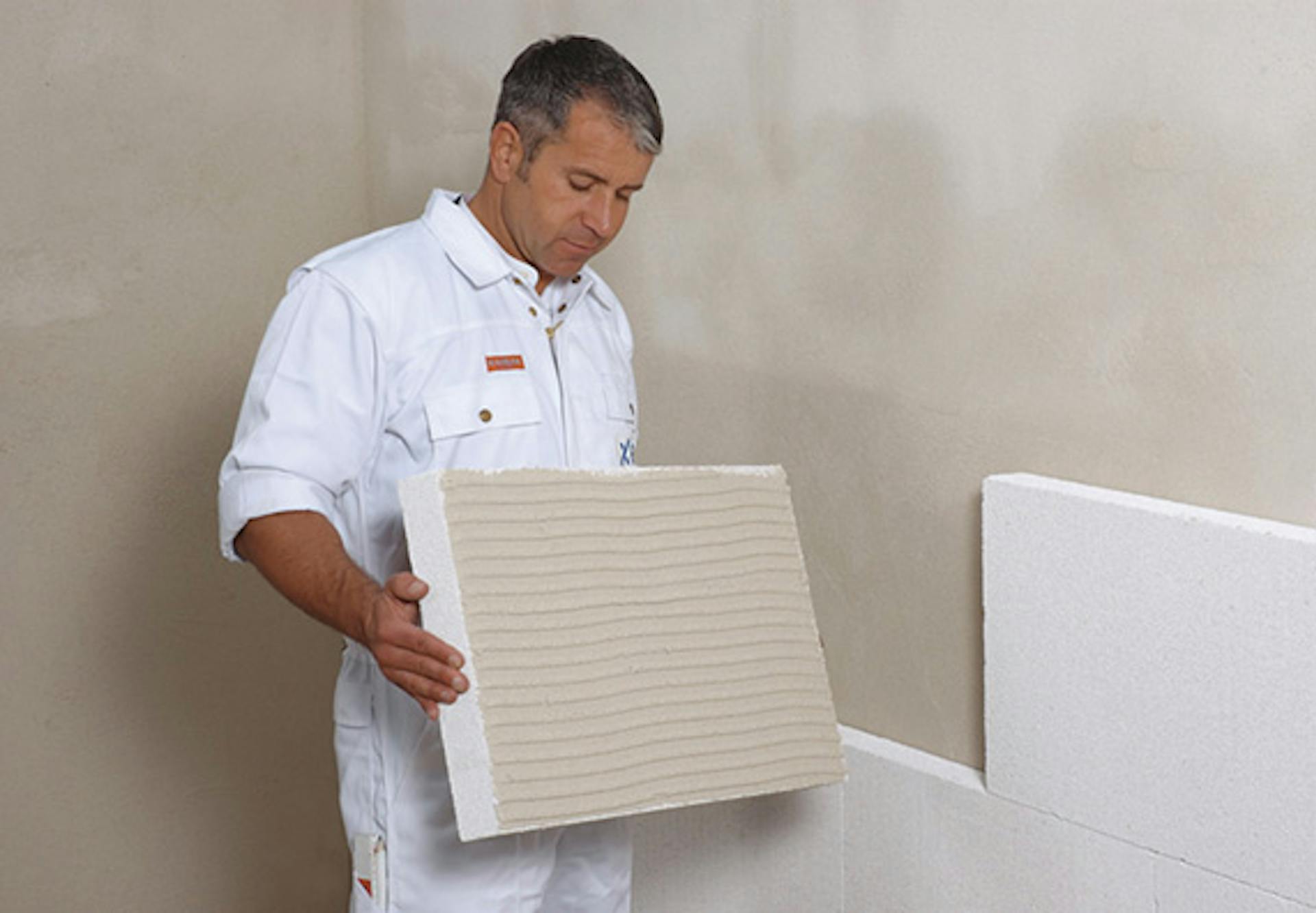 Un appassionato del fai da te posa i pannelli isolanti sulla parete interna.