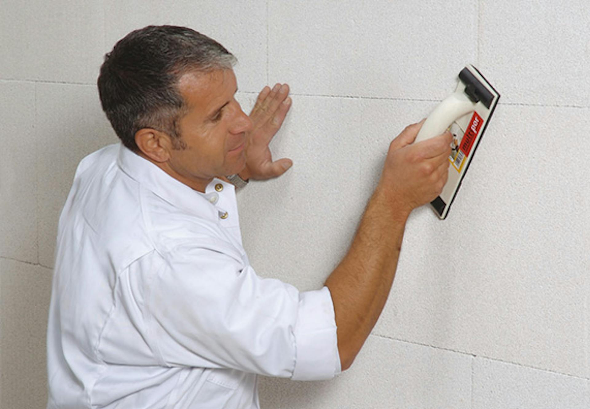 Un appassionato del fai da te leviga l’isolante finito sulla parete interna