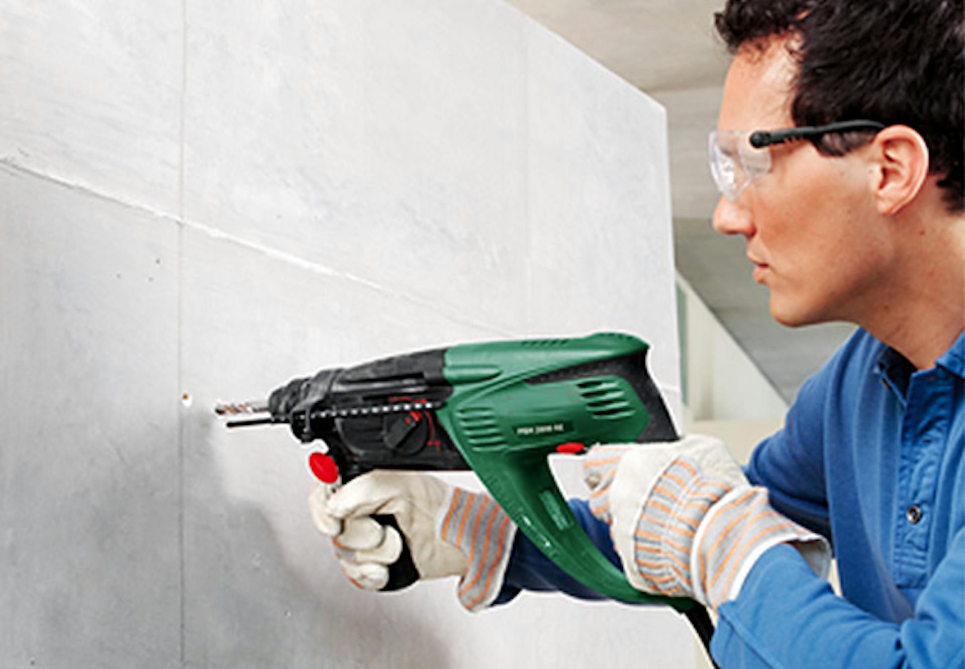 Un appassionato del fai da te pratica un foro per il fissaggio del carico con un trapano nell’isolamento della parete interna.