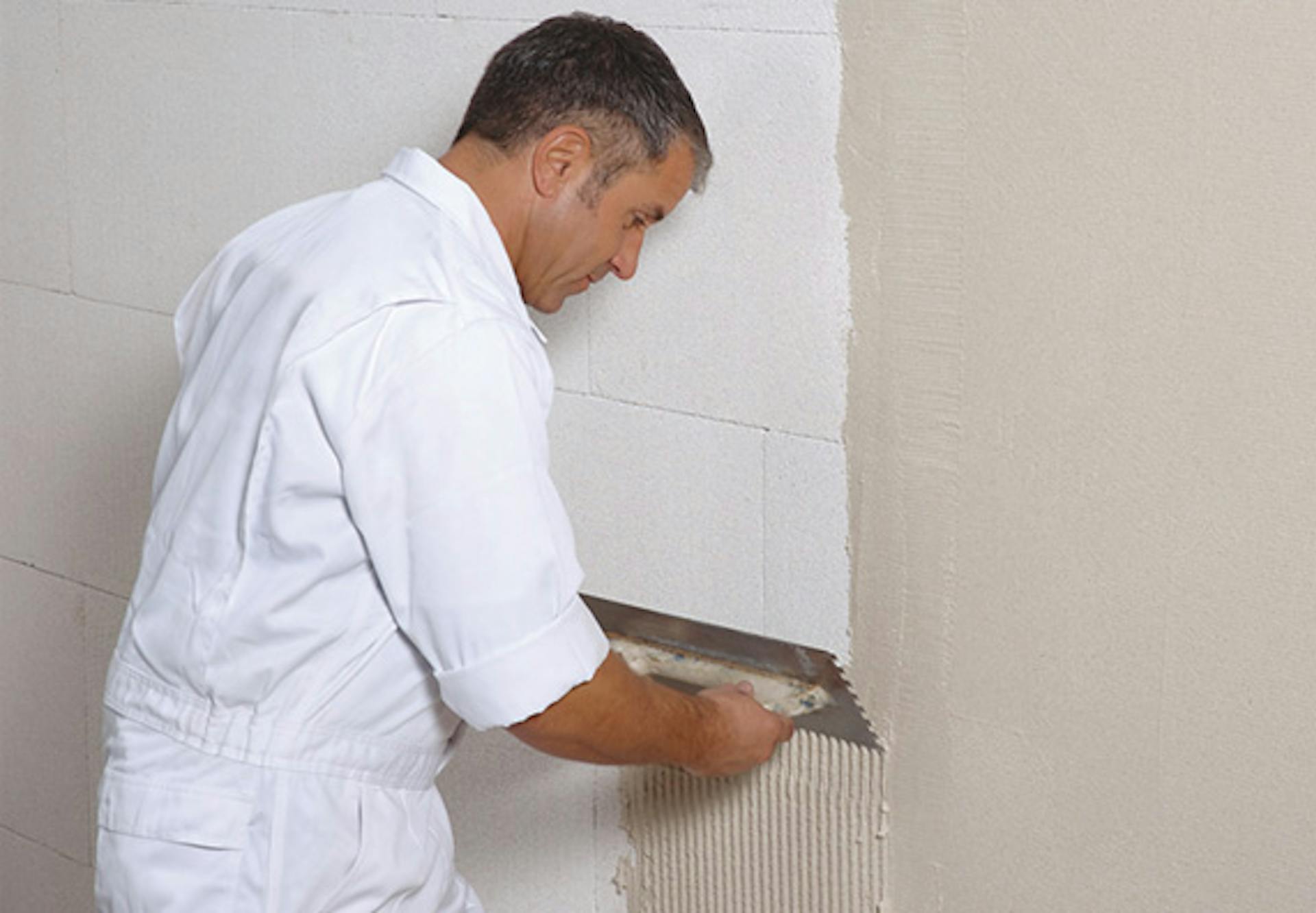 Un appassionato del fai da te applica l’intonaco sull’isolamento della parete.