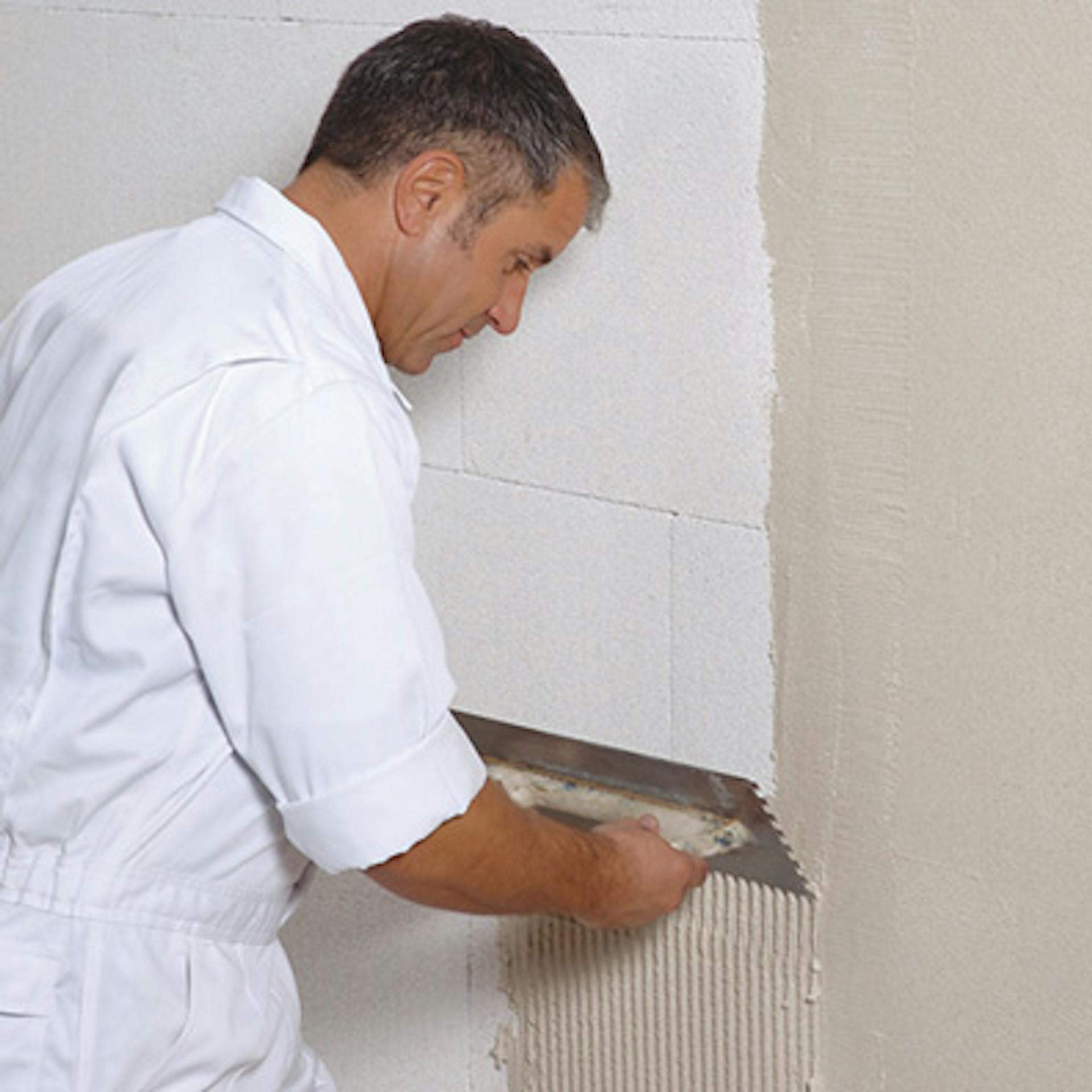 Egy barkácsoló vakolatot ken fel a szigetelésre egy belső falon.