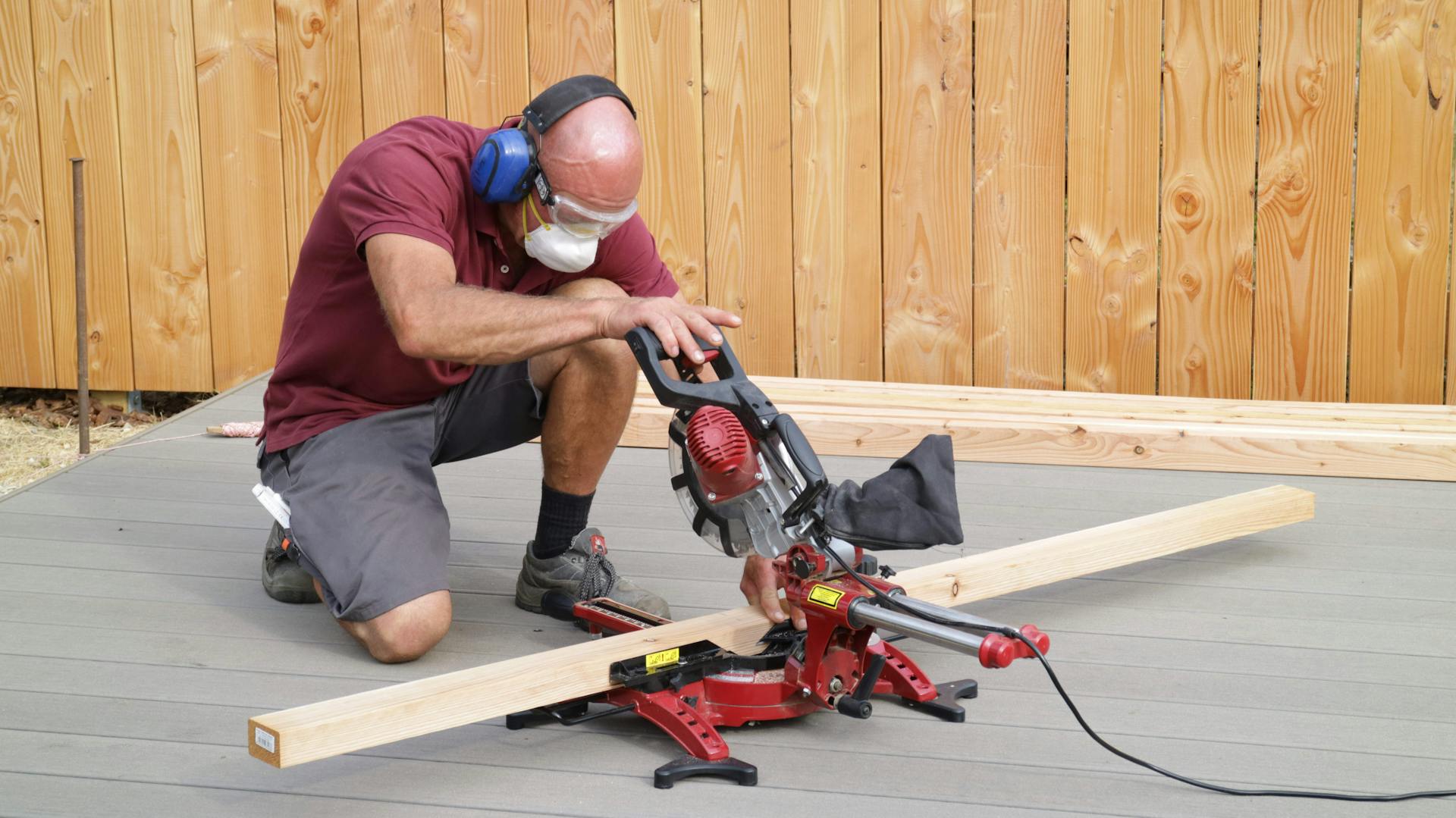 Ein Heimwerker bedient eine Kappsäge, um einen Holzbalken zu schneiden.