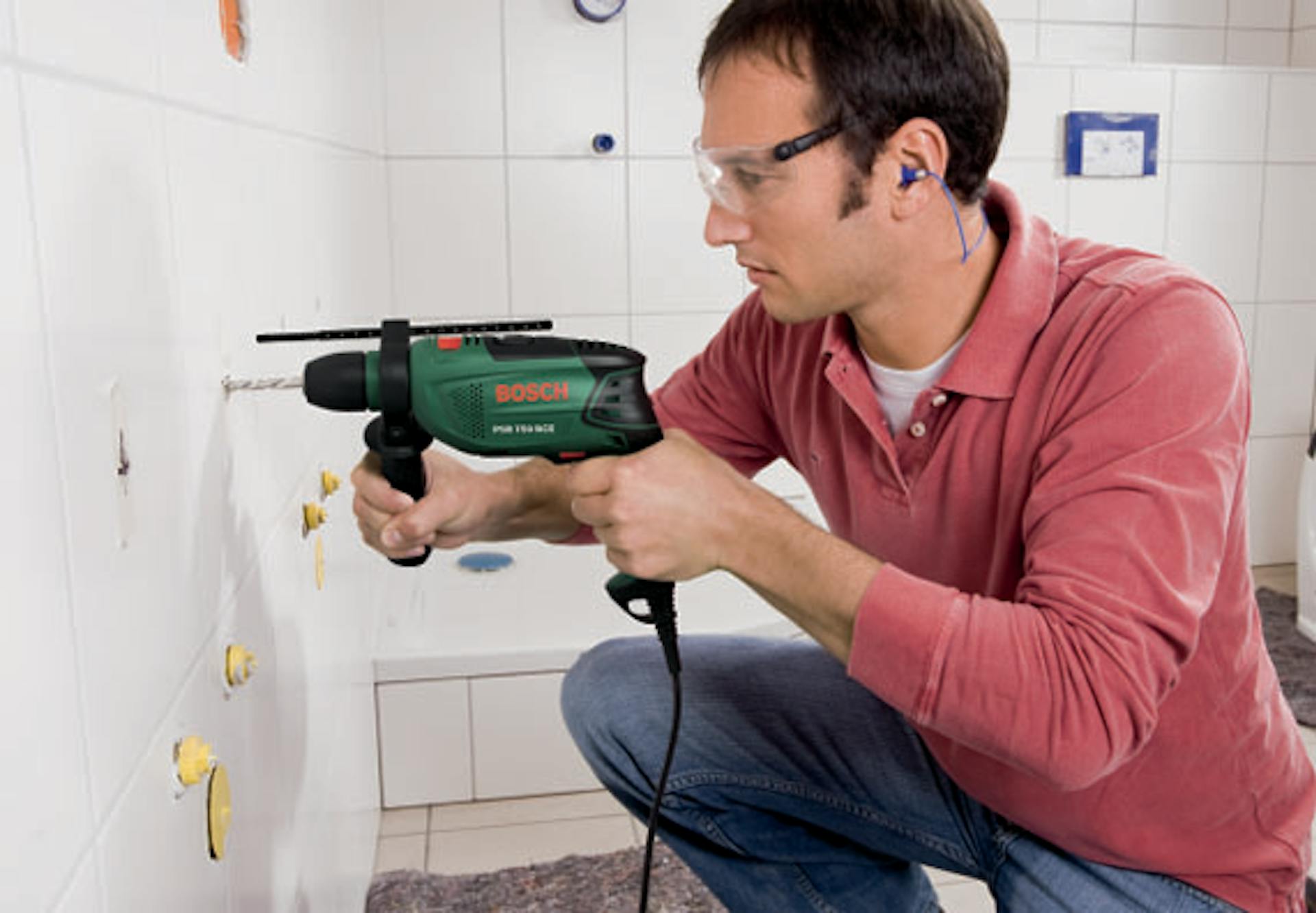 Una persona realizza un foro nella parete piastrellata