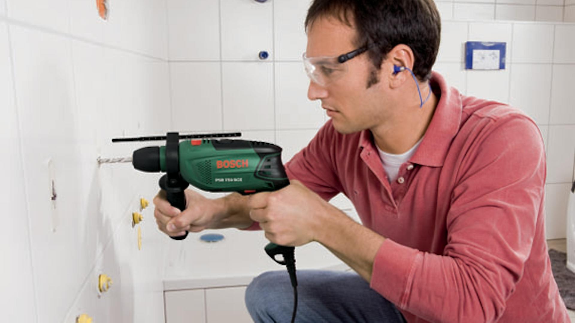 Mann bohrt Loch in Fliesenwand