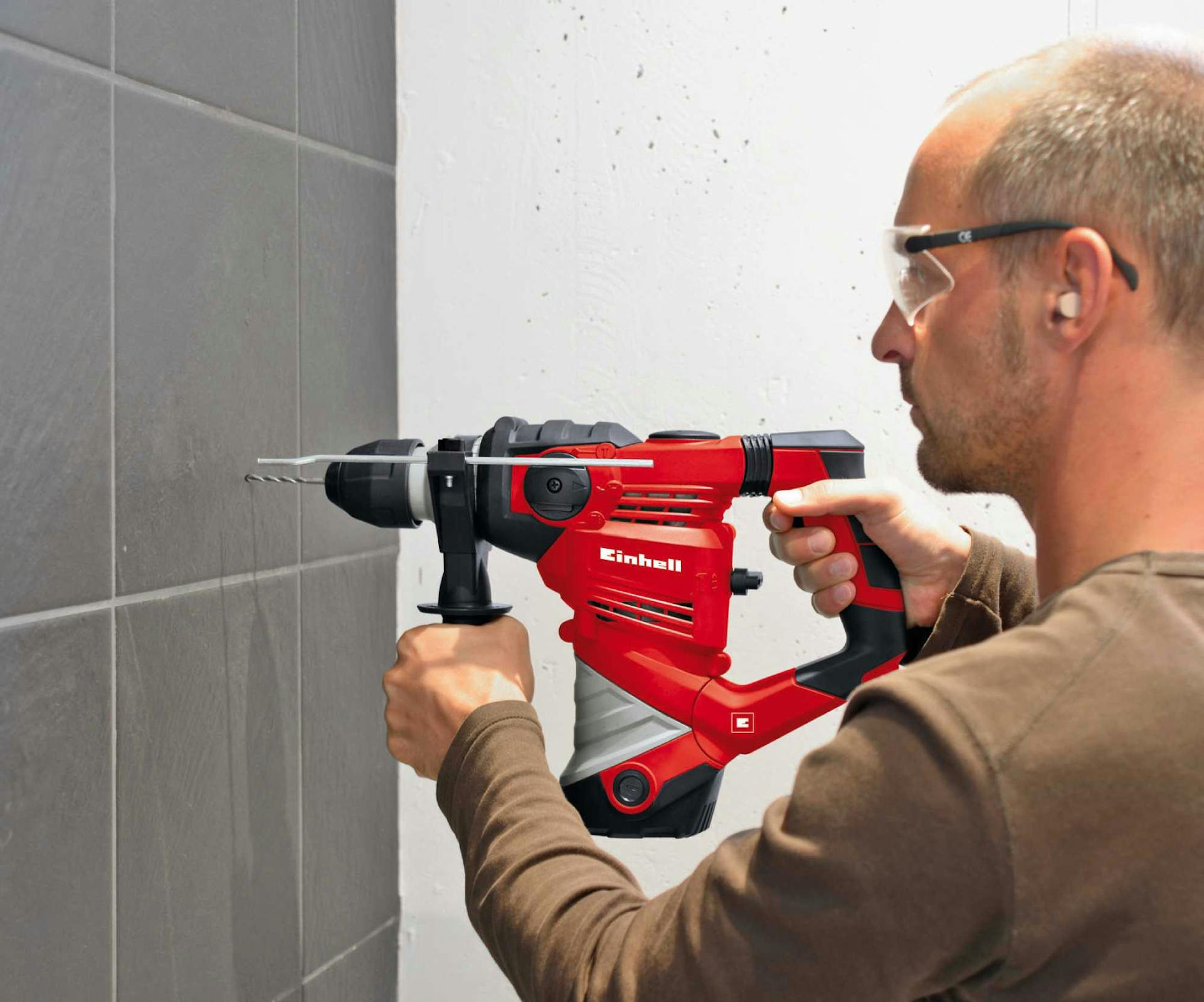 Un uomo pratica un foro nelle piastrelle con un trapano